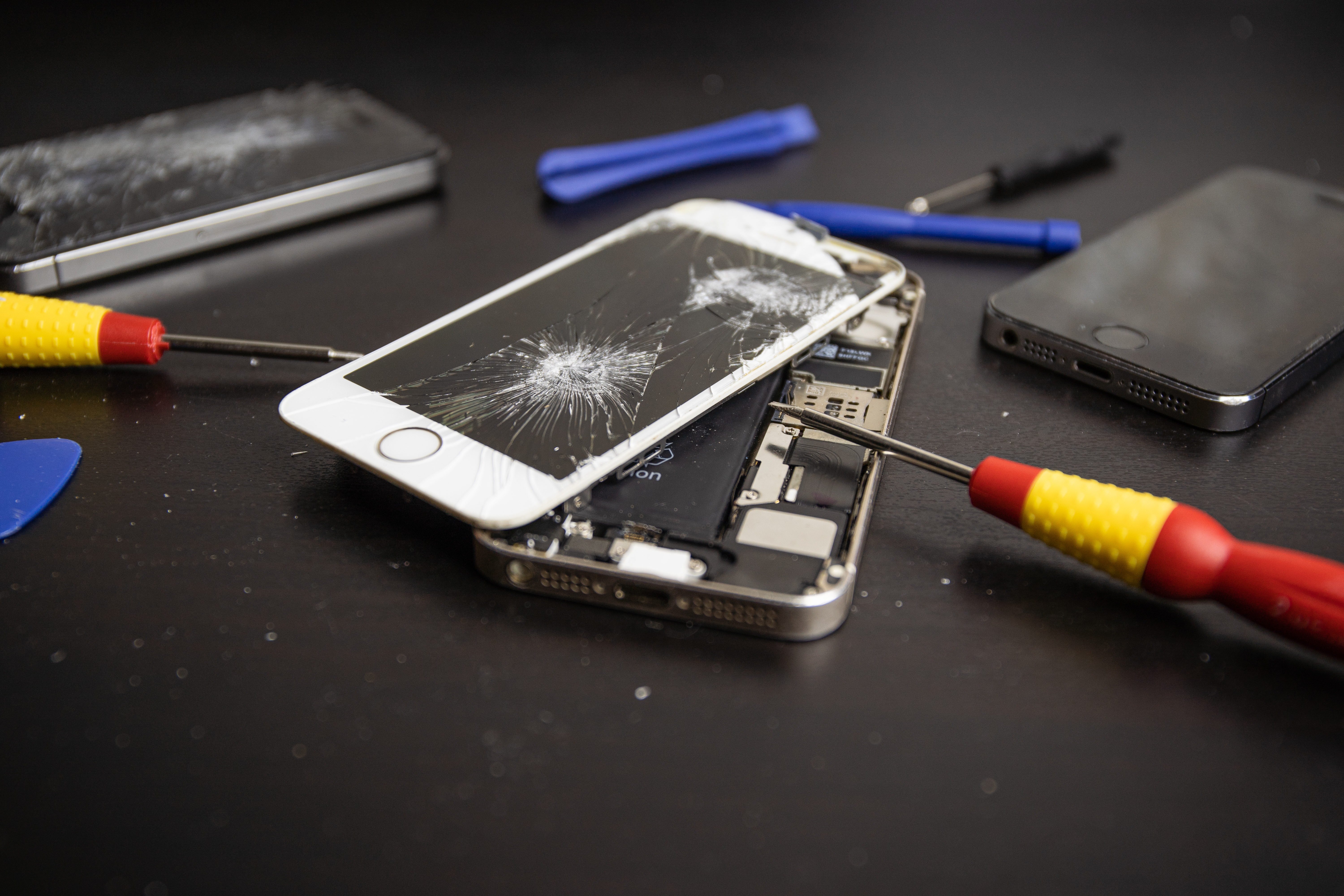 White iPhone with a cracked screen being repaired