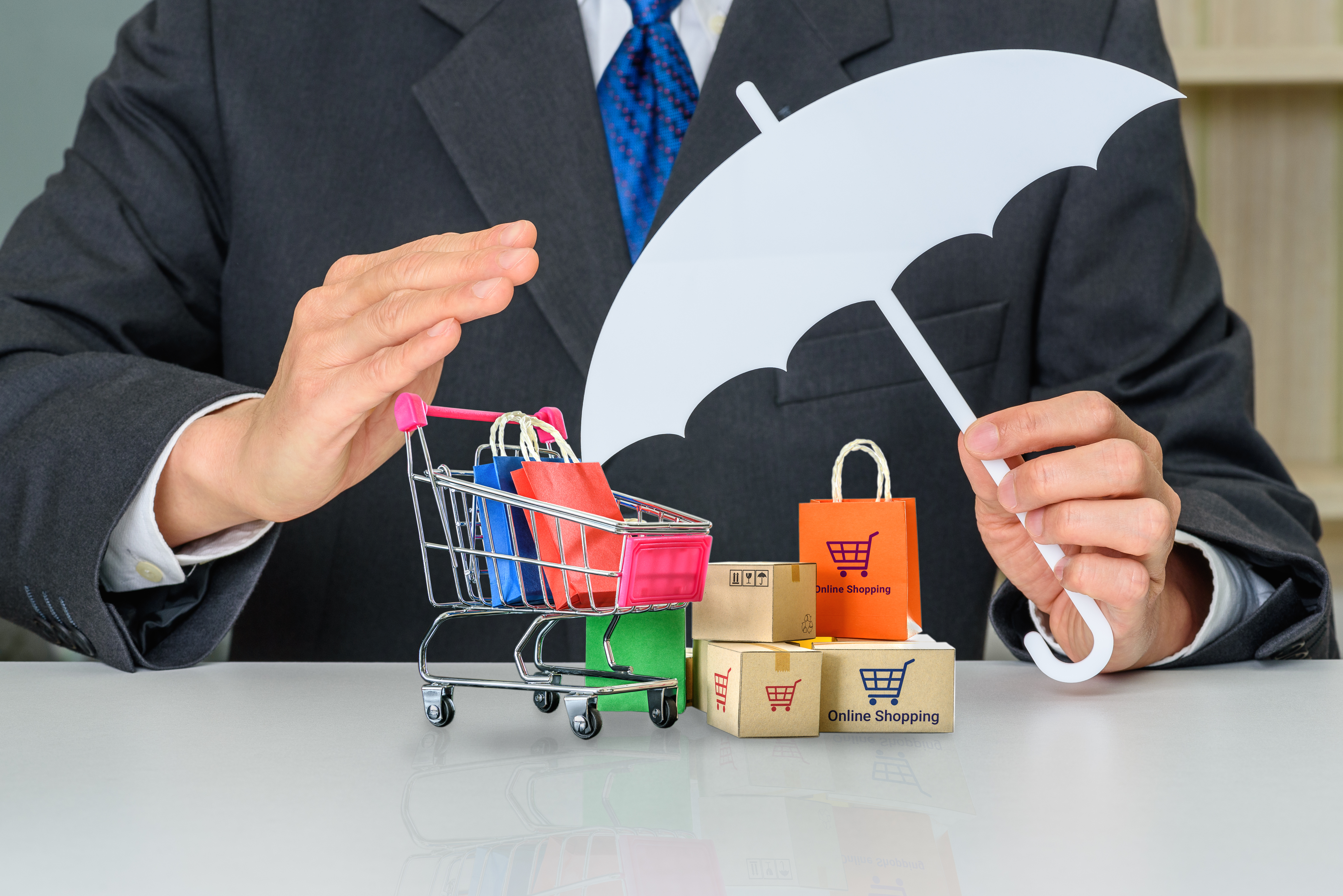 Man holding an umbrella over a shopping cart full of items