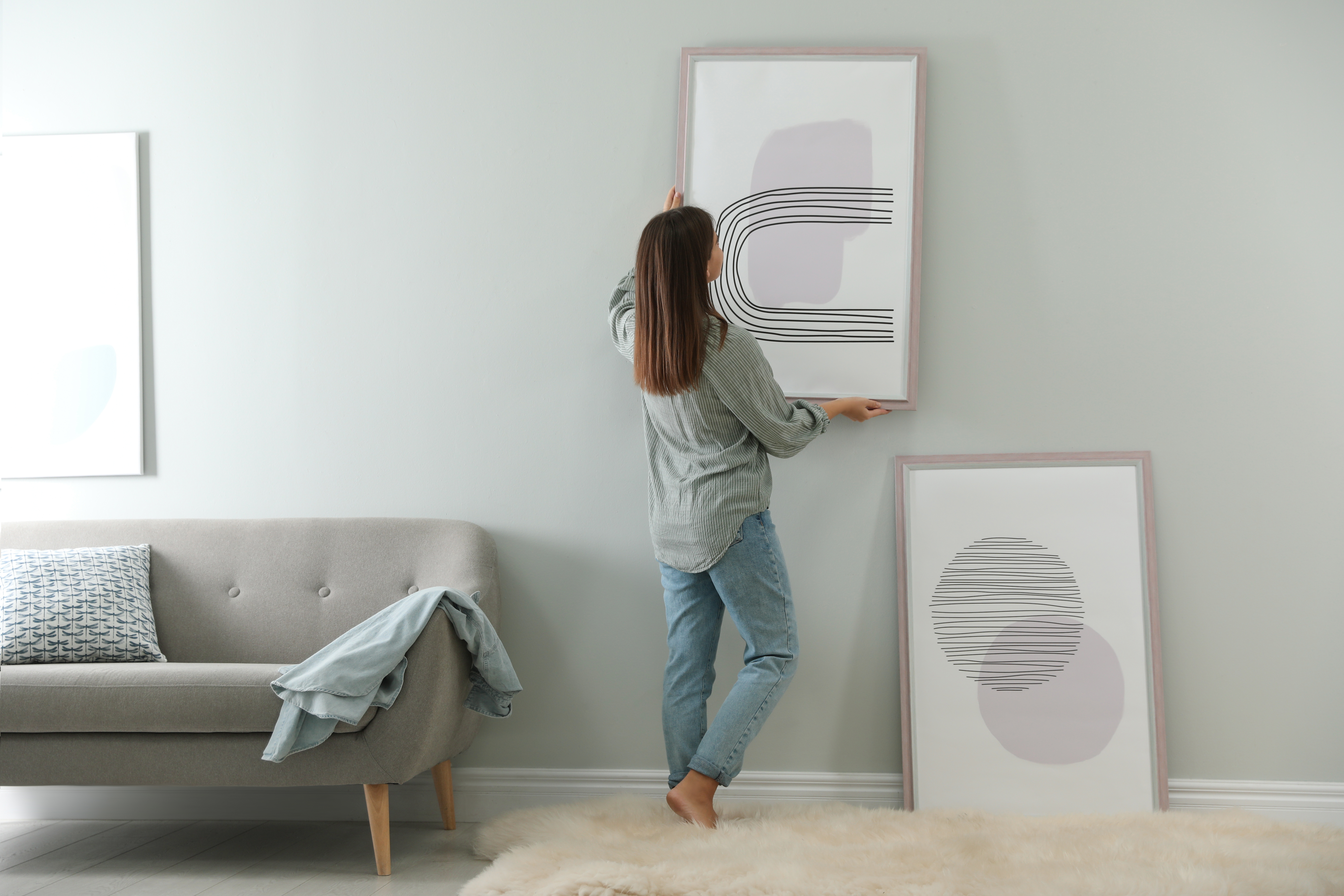 Woman hanging wall art in her living room