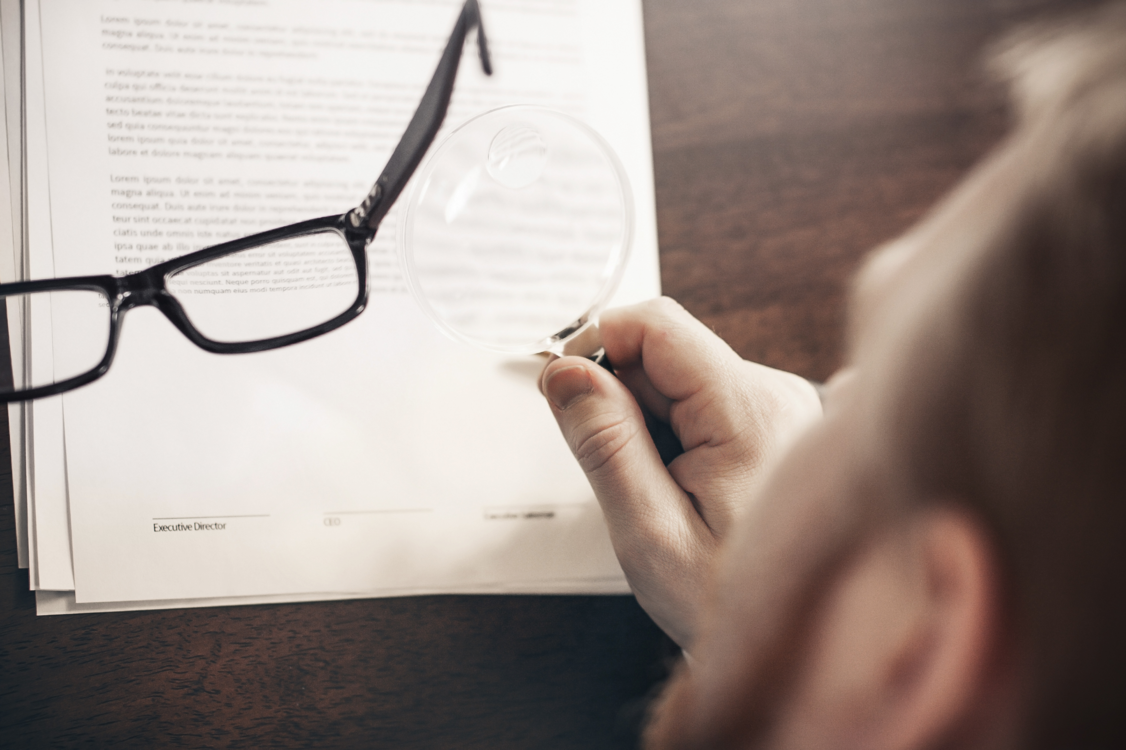 Man reading an agreement with a magnifying glass