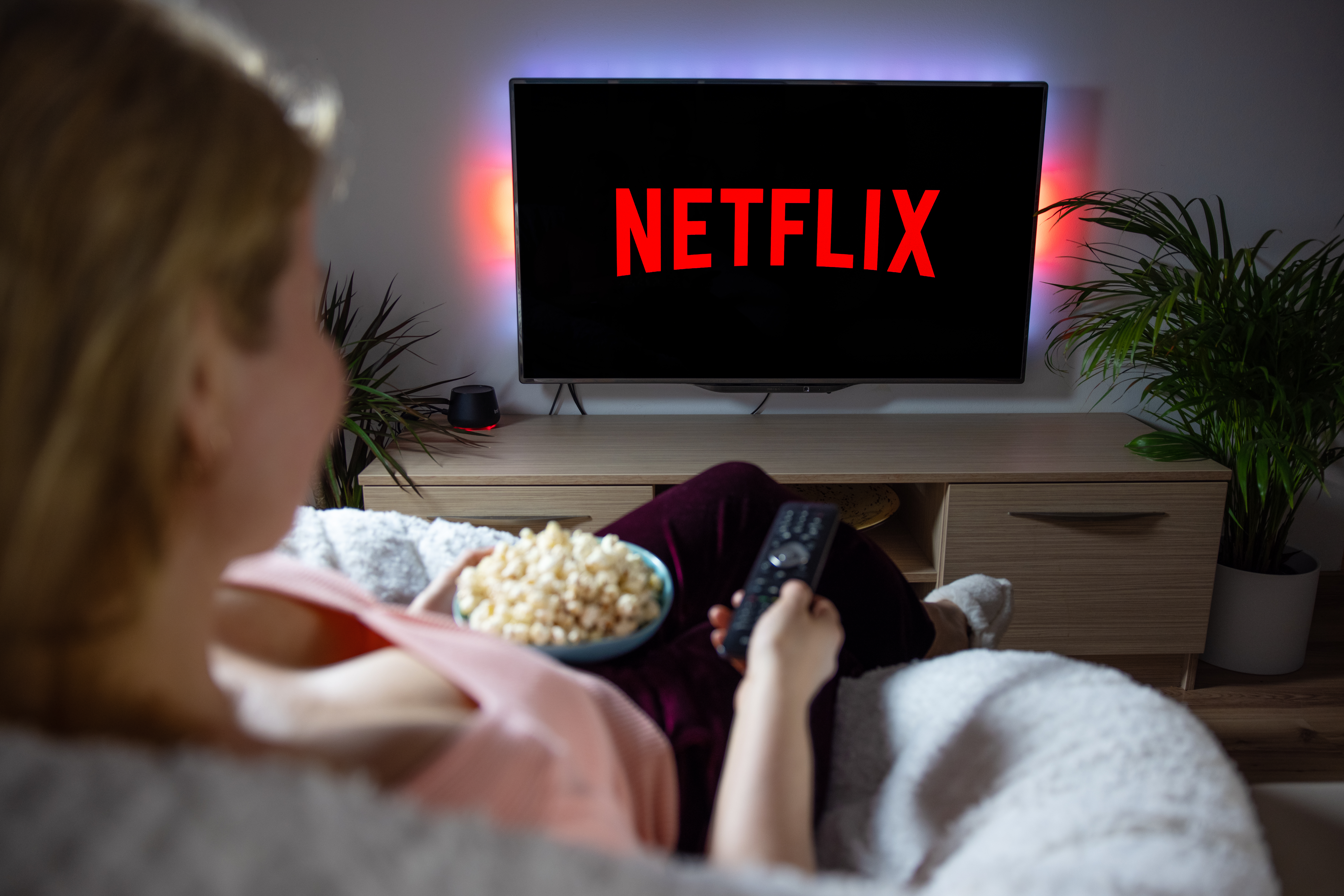 Woman sitting on the couch eating popcorn and watching Netflix