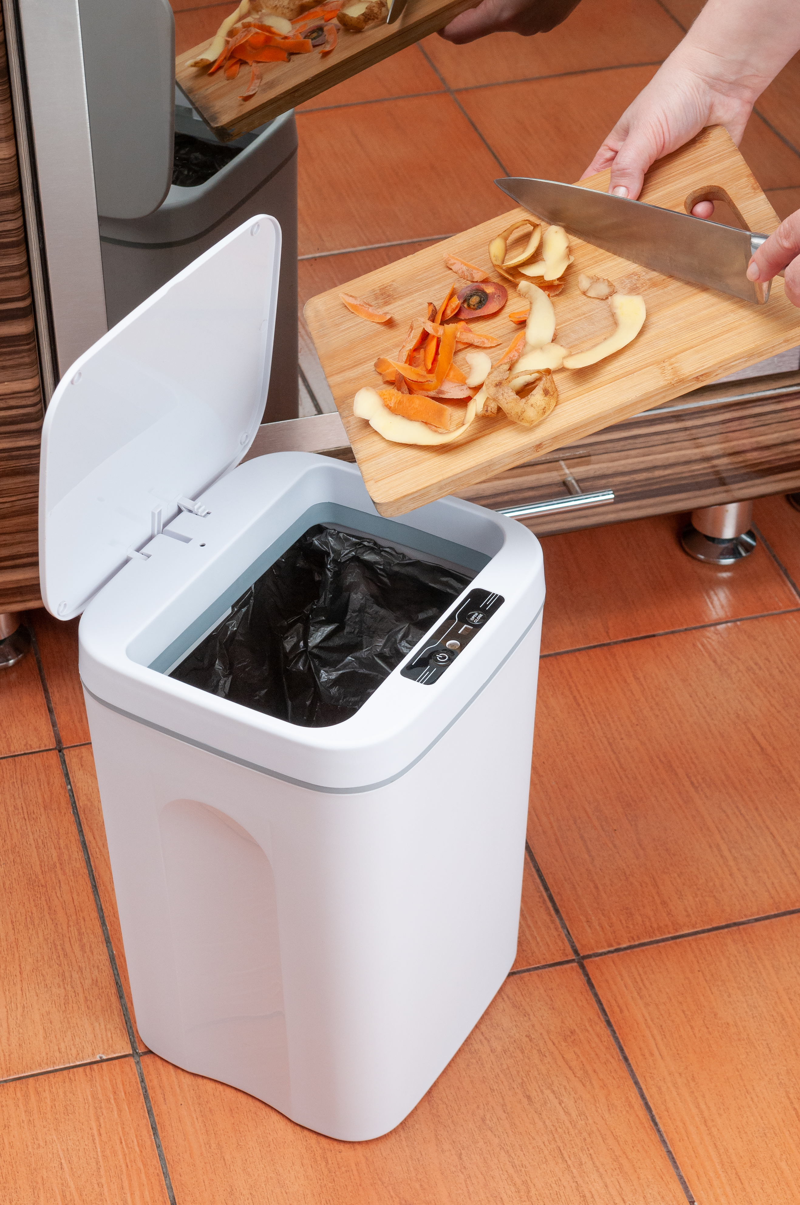 Person placing food scraps into a smart trash can