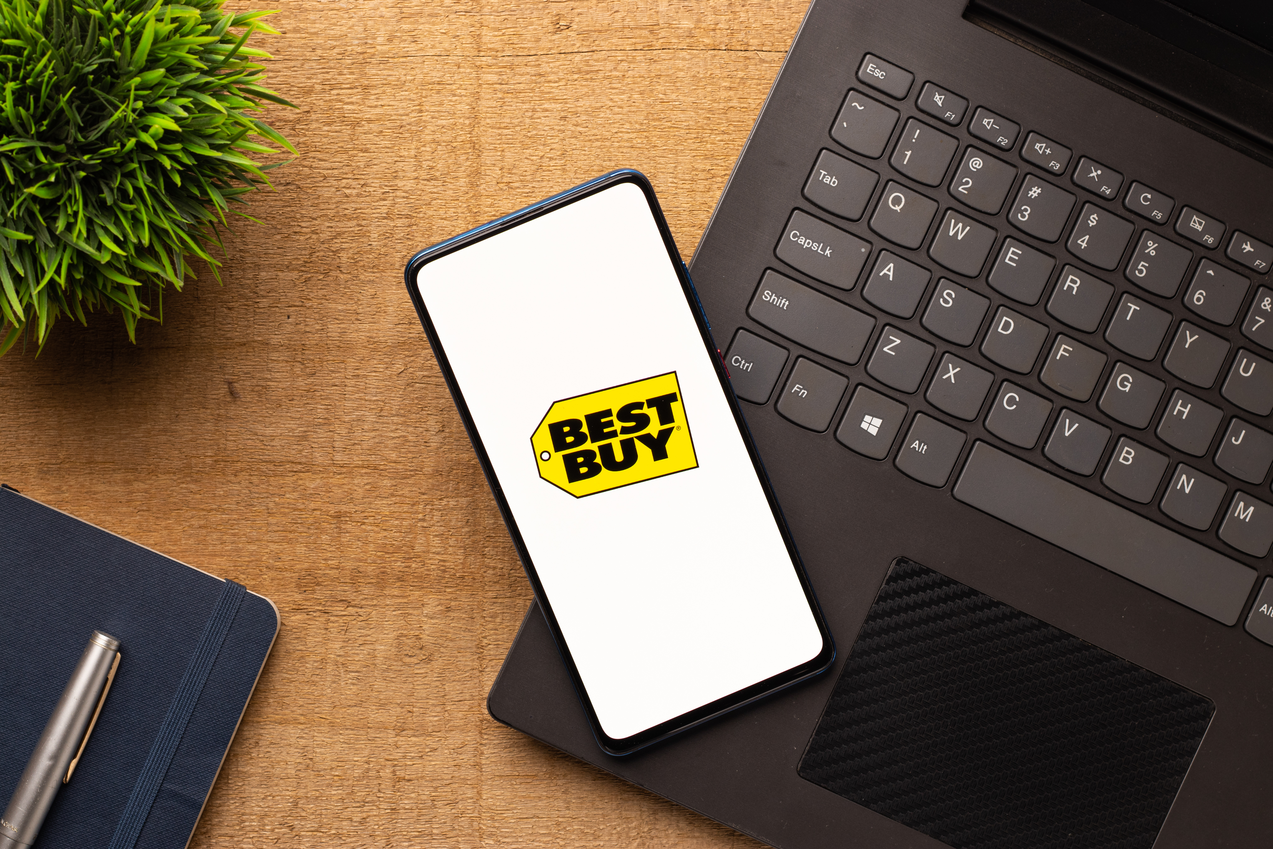 Smartphone showing the Best Buy logo sitting on top of a laptop