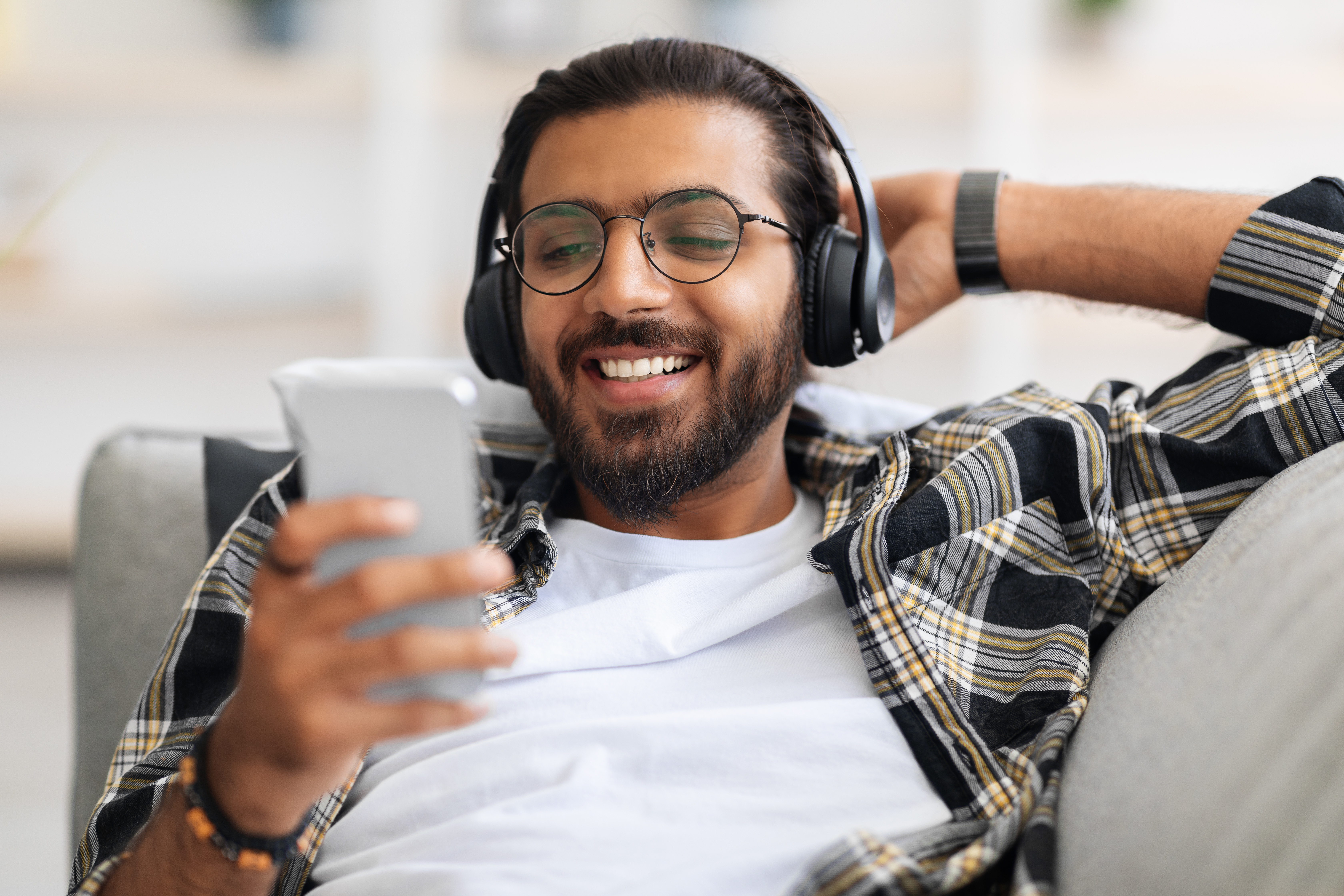 Young man relaxing looking at his phone and listening to music on headphones