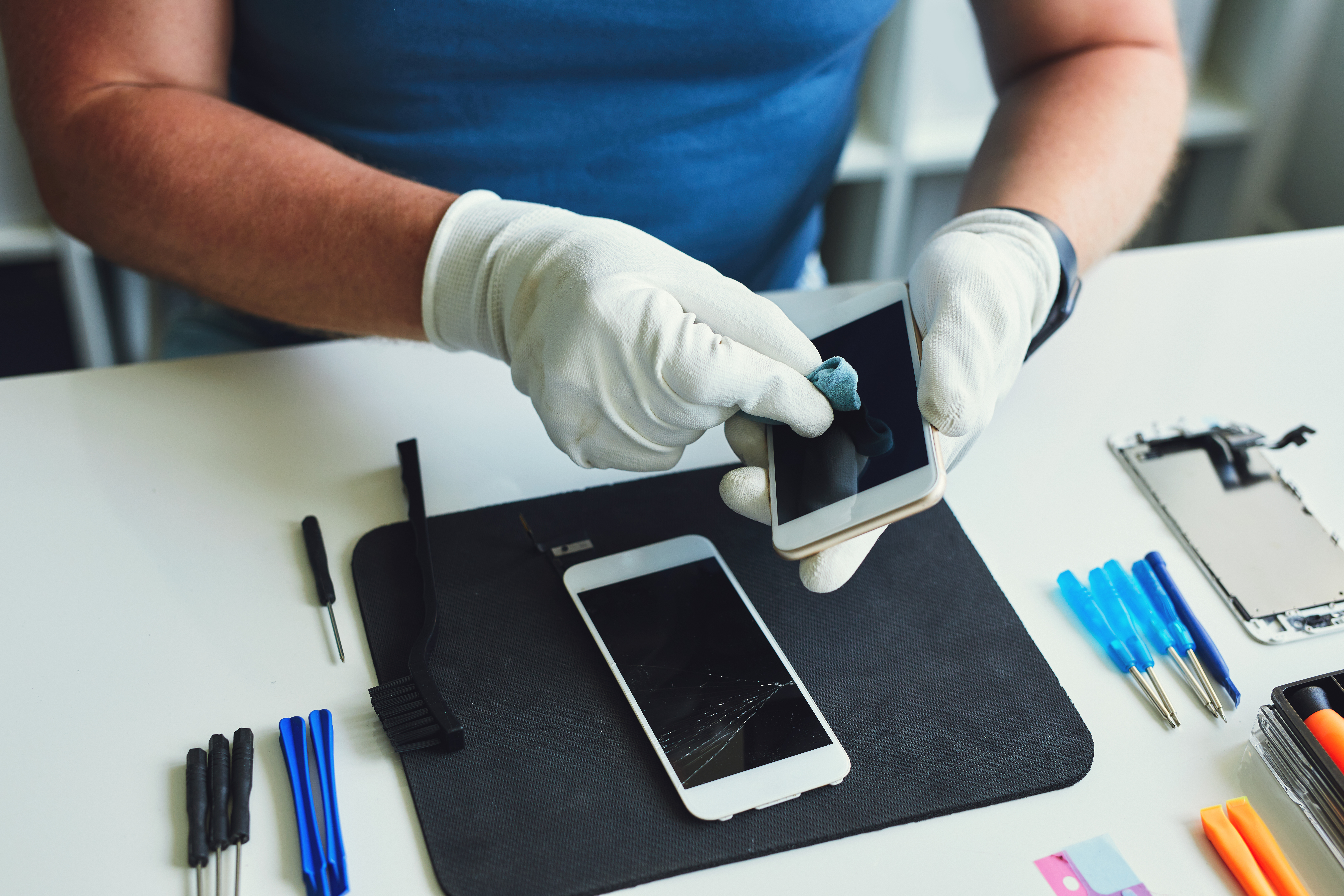 Person repairing two white iPhones