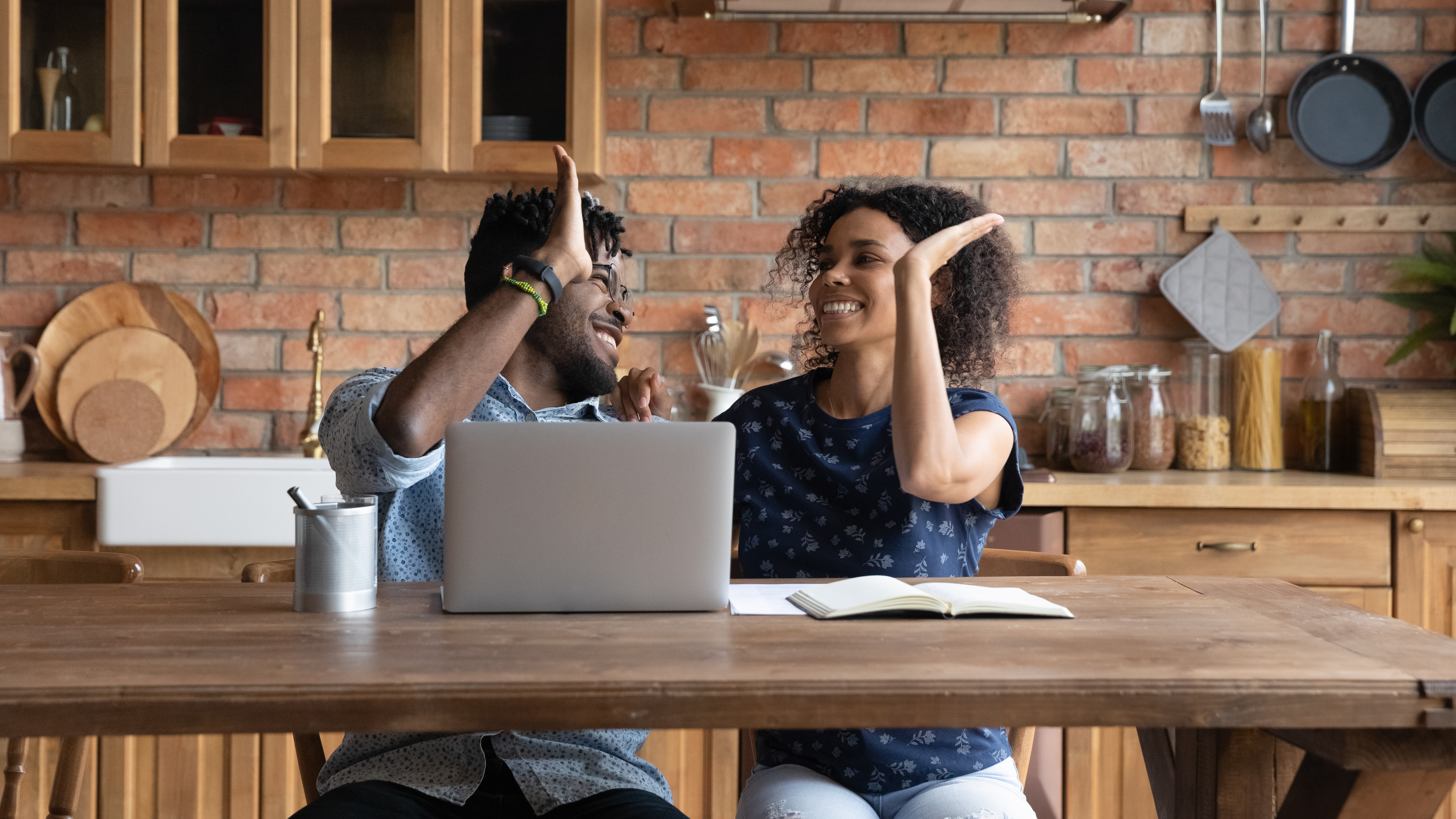 Man and woman sitting at a table high-fiving each other