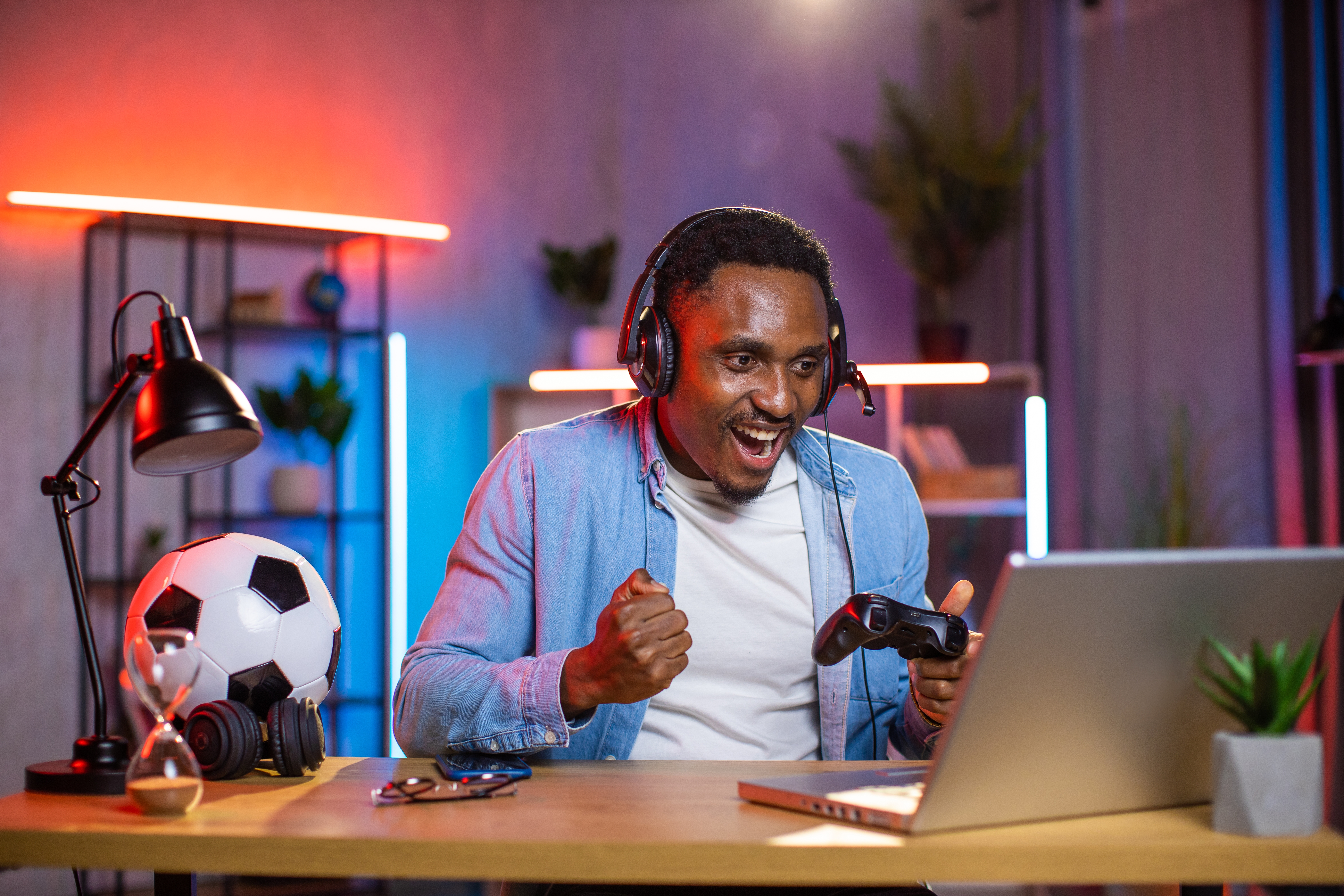 Man sitting at a desk playing a video game on his laptop