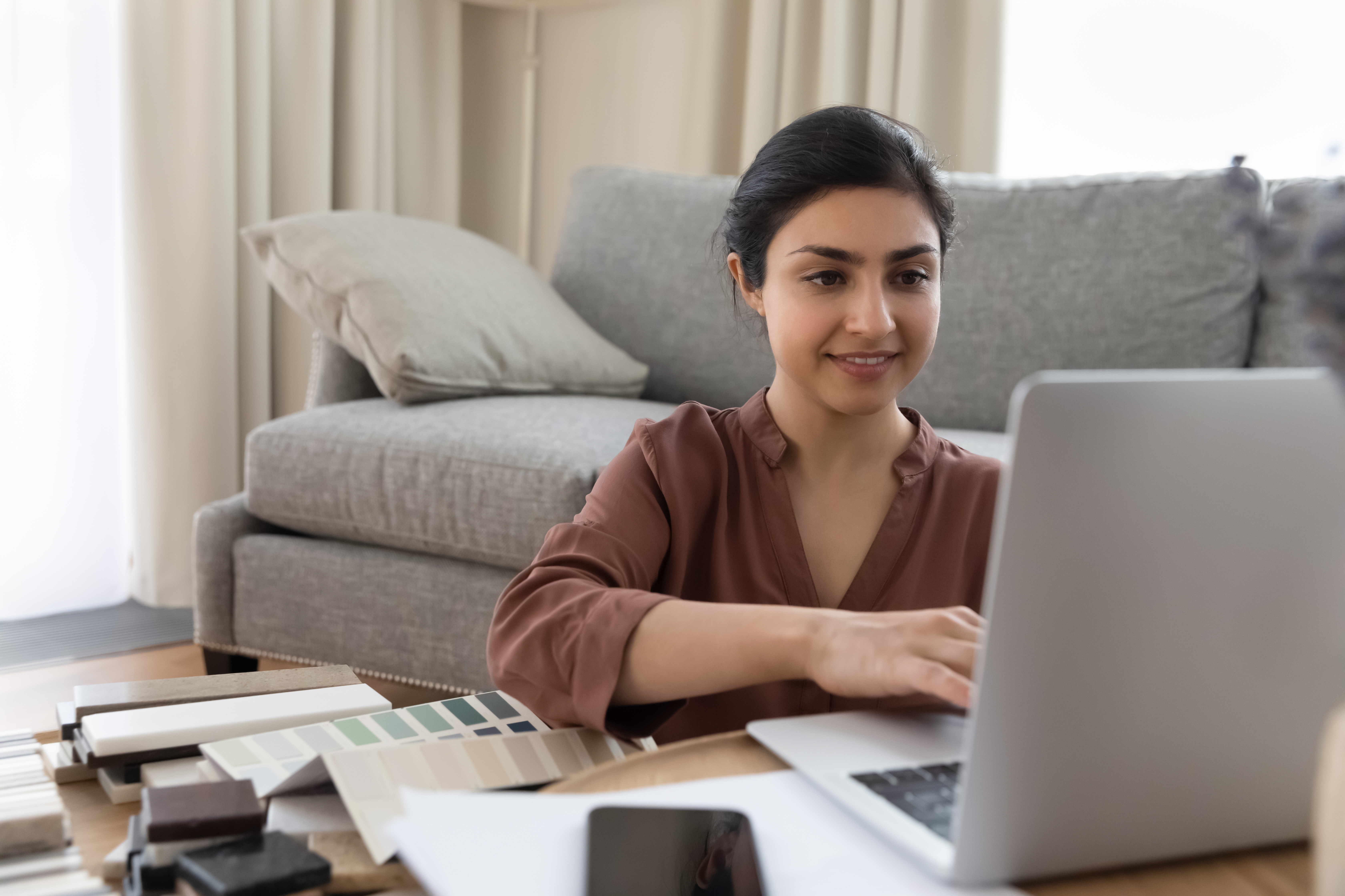 Woman looking at her laptop surrounded by paint swatches