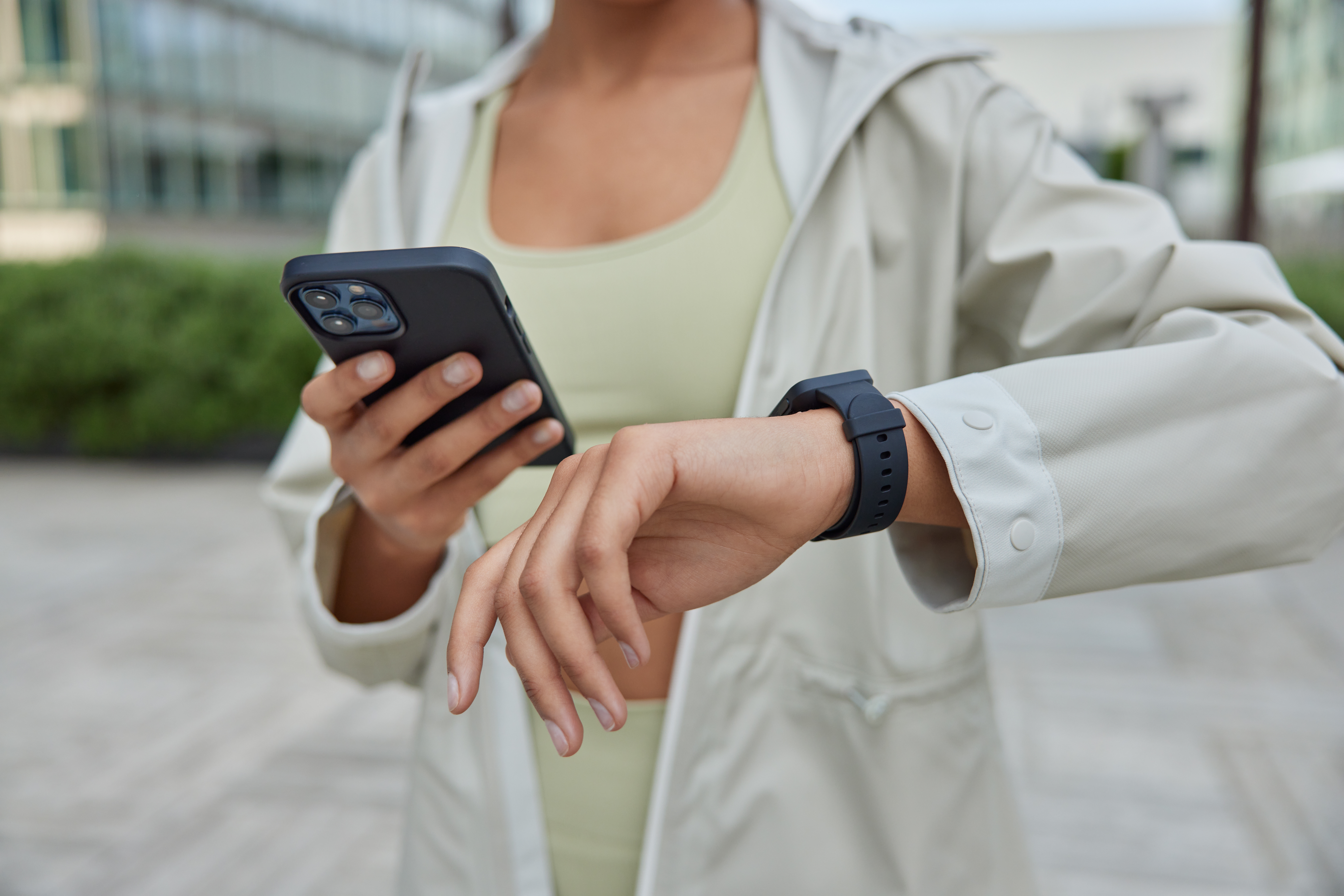 Woman looking at her smartwatch and holding her phone