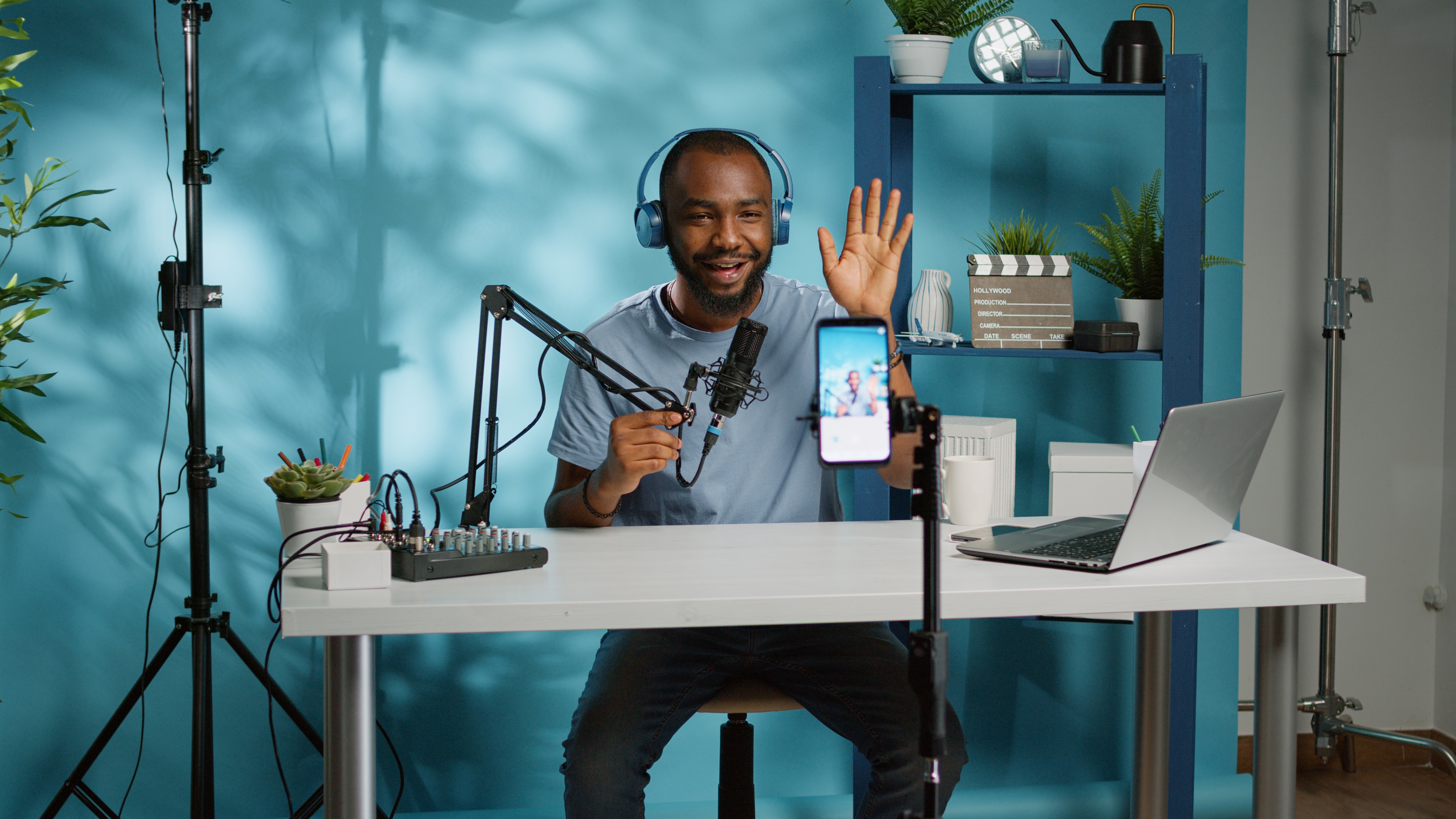 Man sitting at a desk recording himself on a smartphone and speaking into a microphone