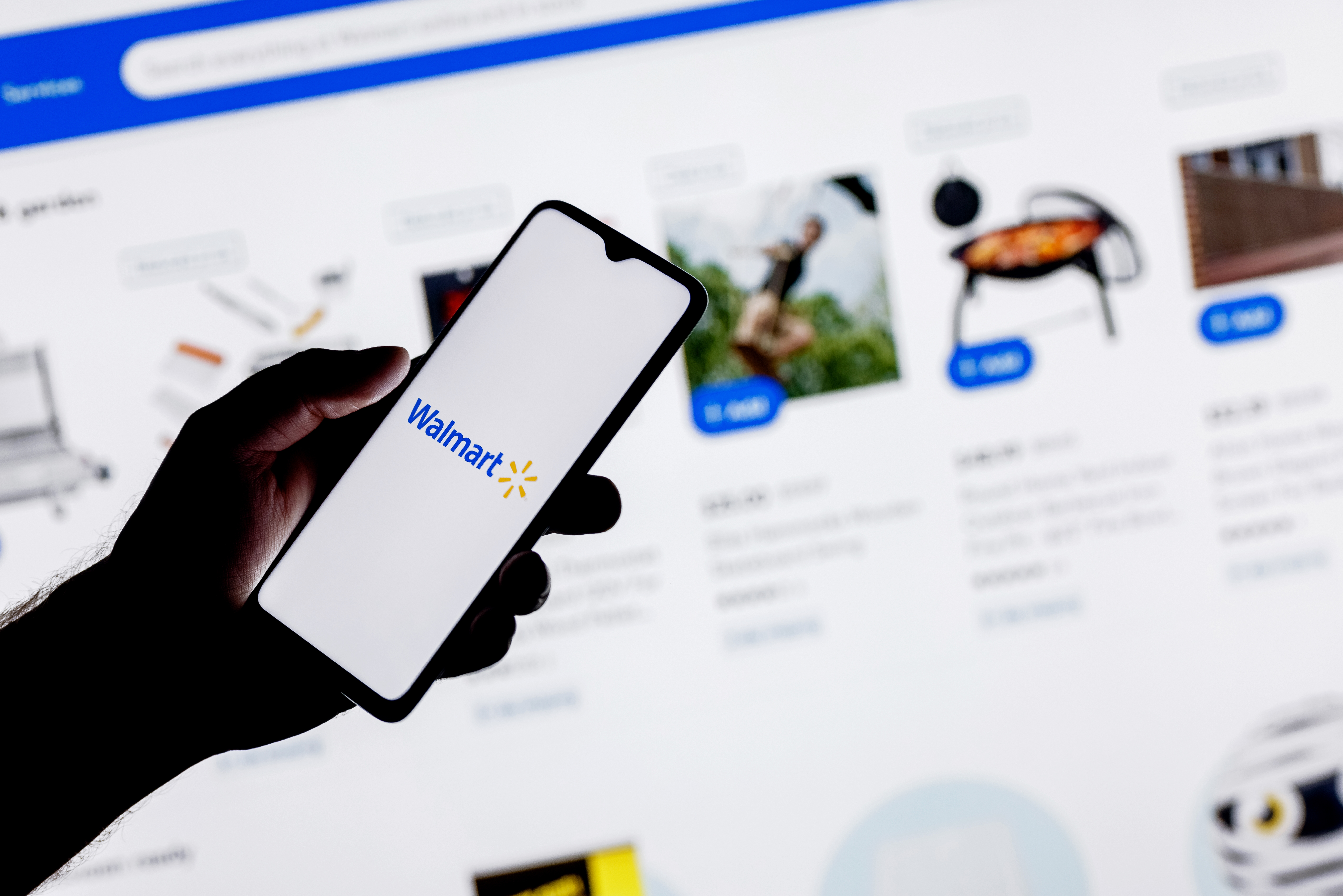 Person holding a smartphone with the Walmart logo on it