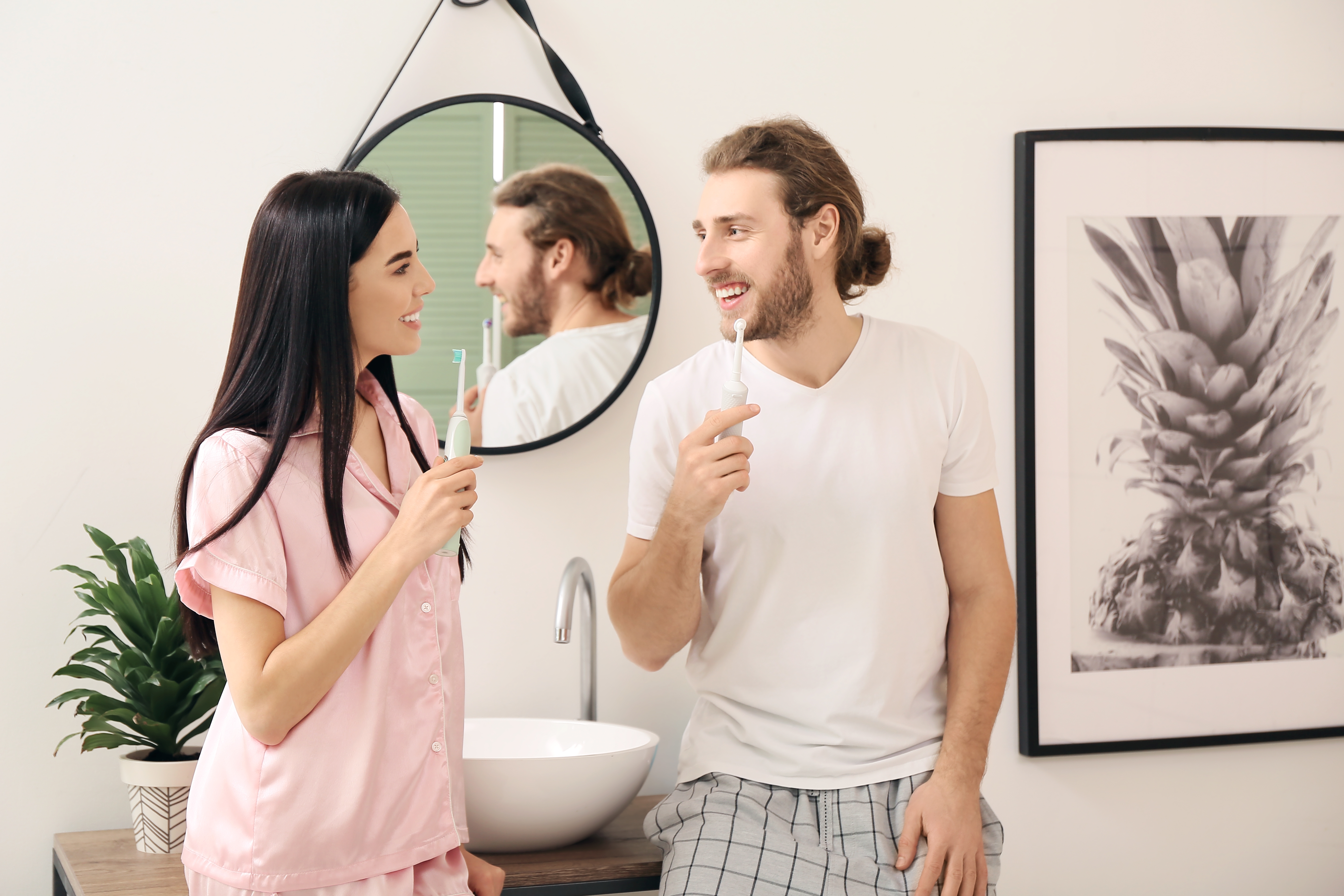 Man and woman holding electric toothbrushes