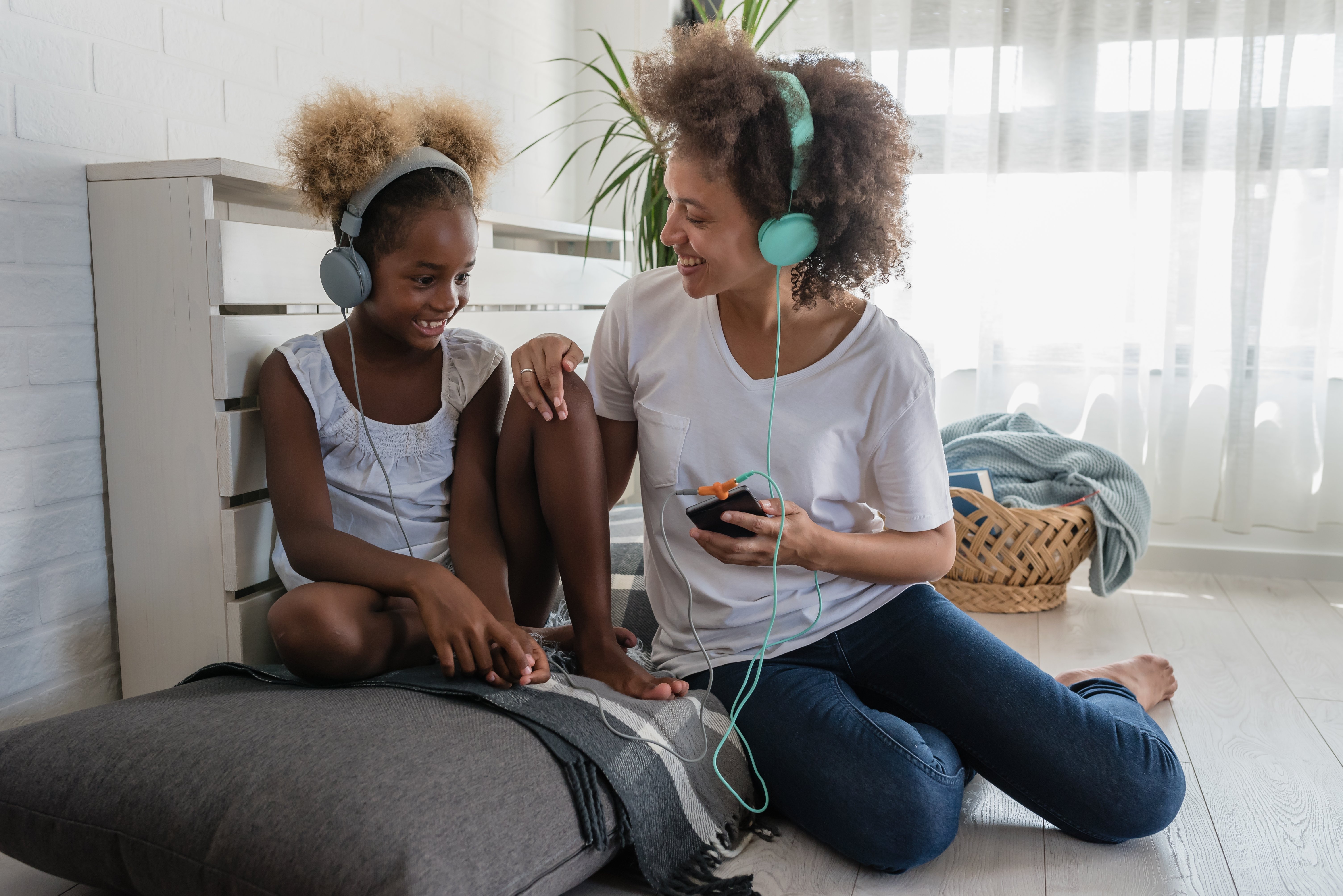 Mom and daughter with headphones on listening to music together