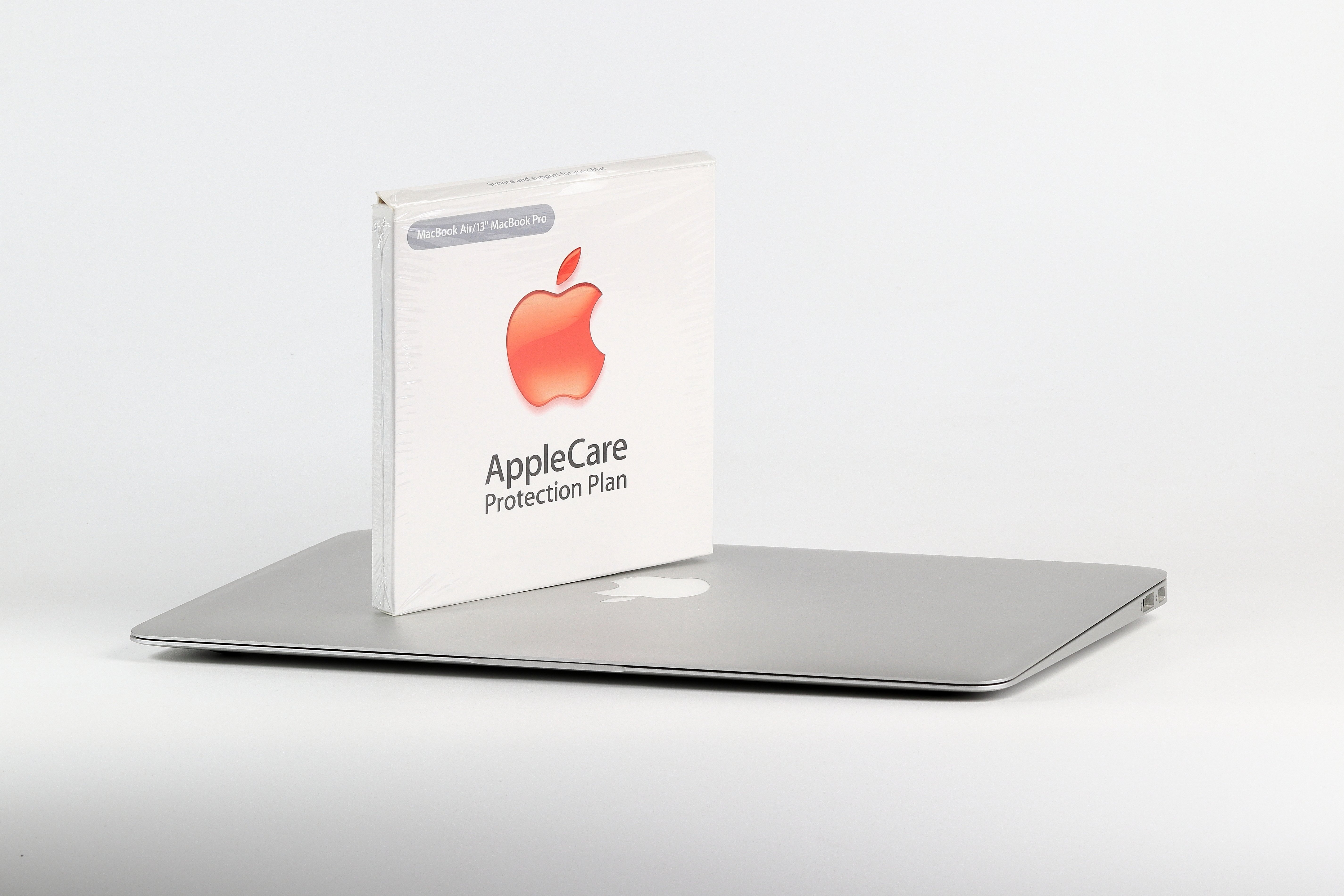 Closed MacBook sitting on a table with an AppleCare pamphlet on top of it