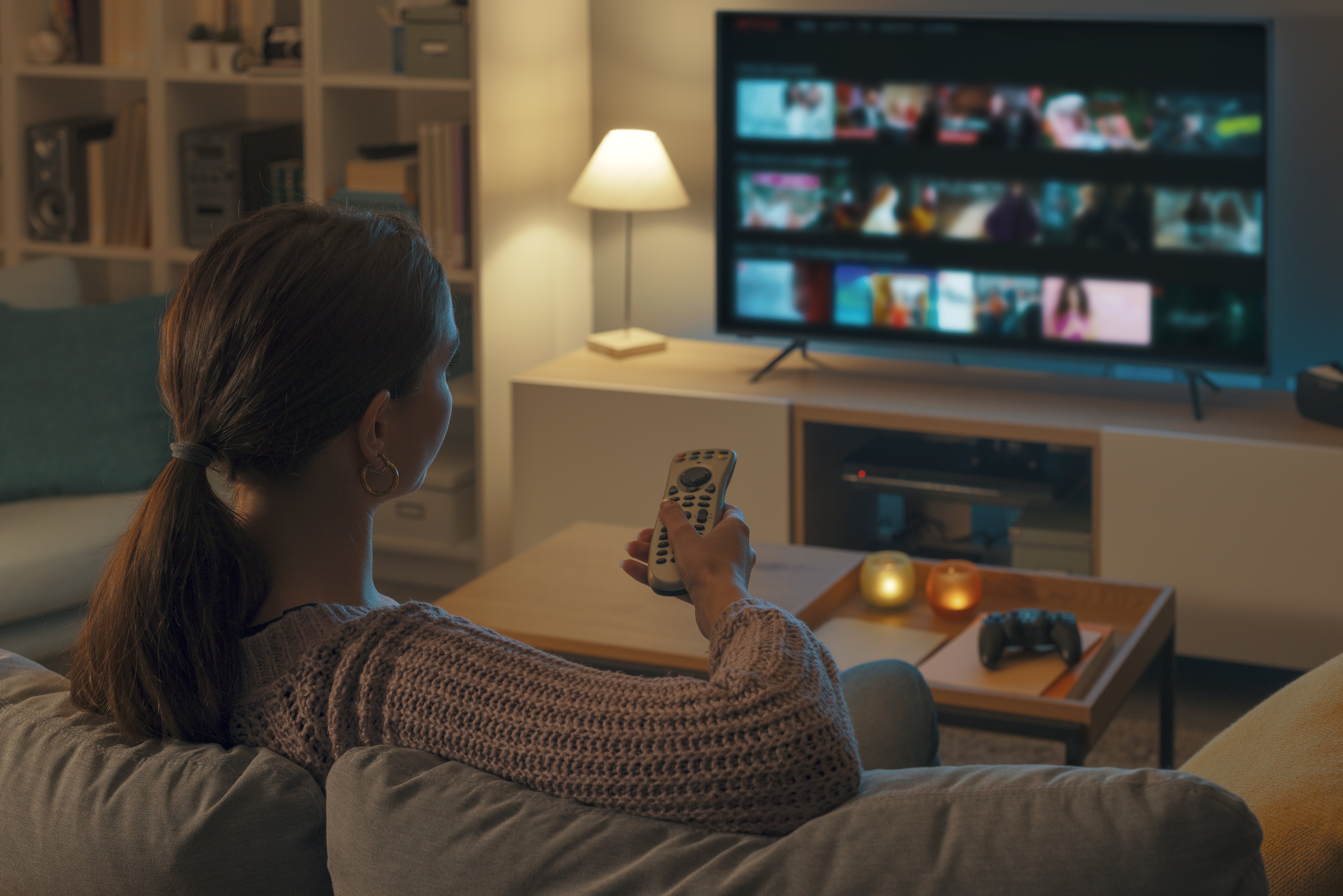 Woman sitting on couch looking for something to watch on tv