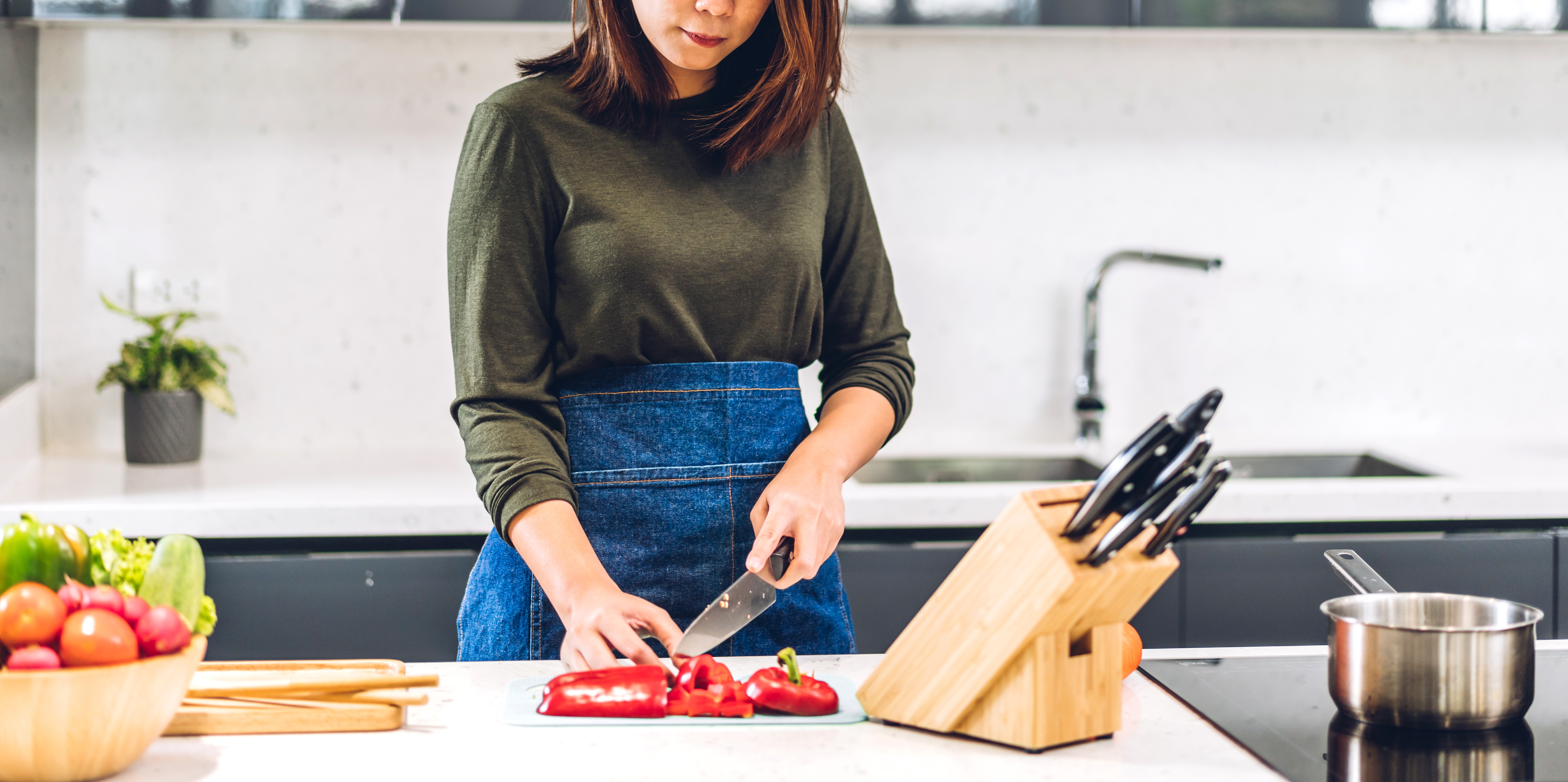 Woman cutting a red pepper with a kitchen knife