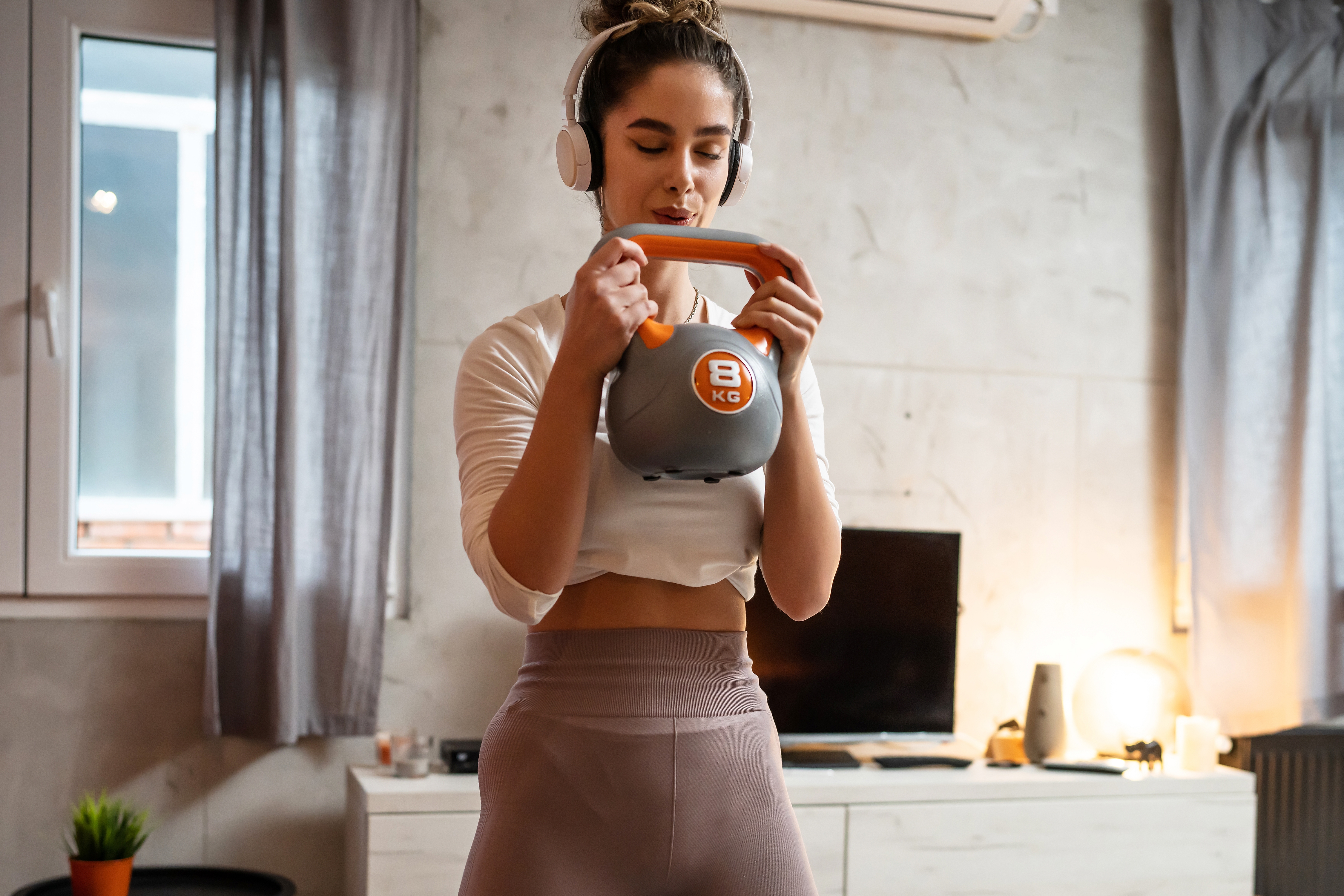 Woman wearing headphones working out with a kettlebell