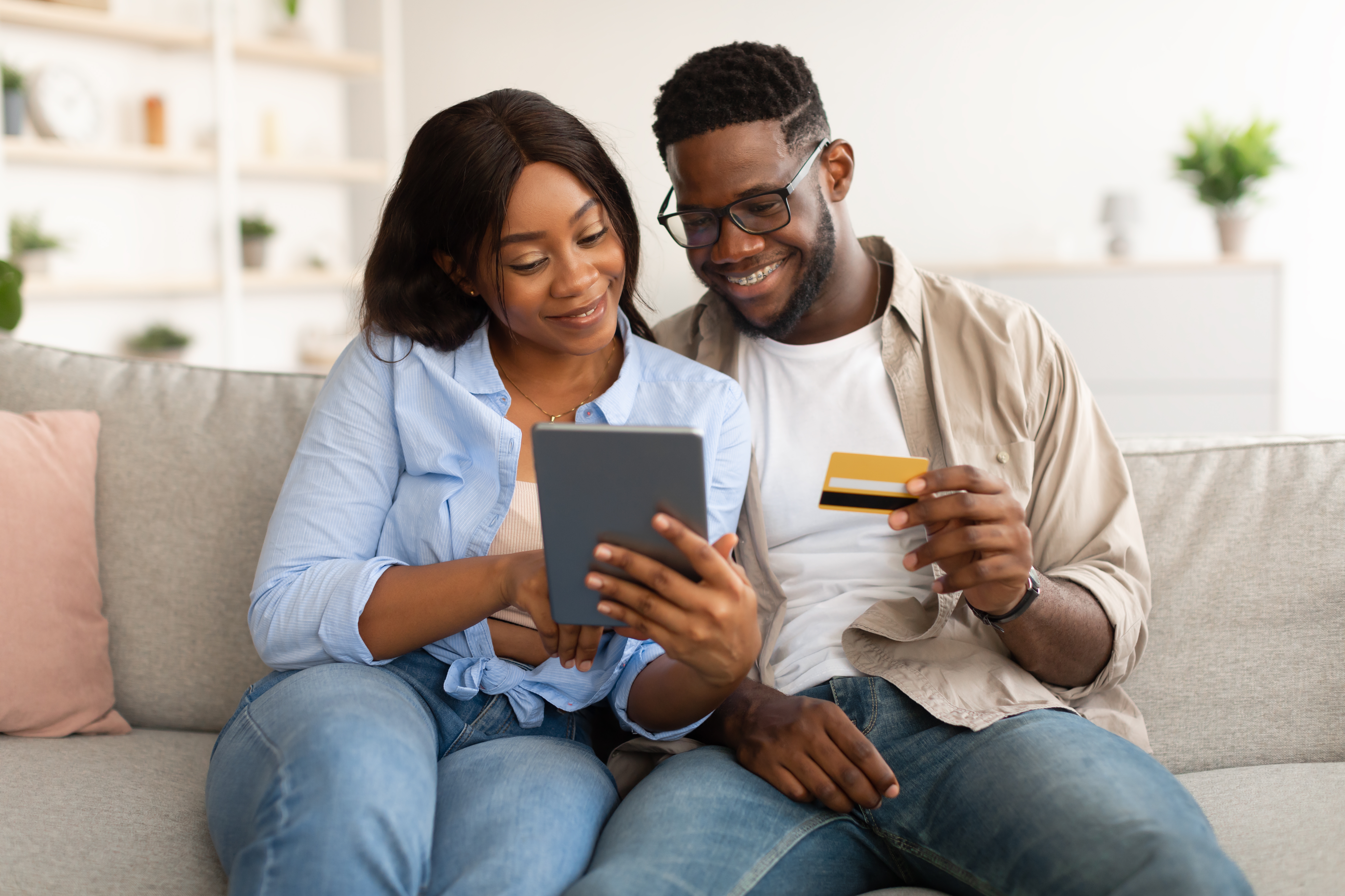 Man and woman sitting on the couch together buying something on a tablet