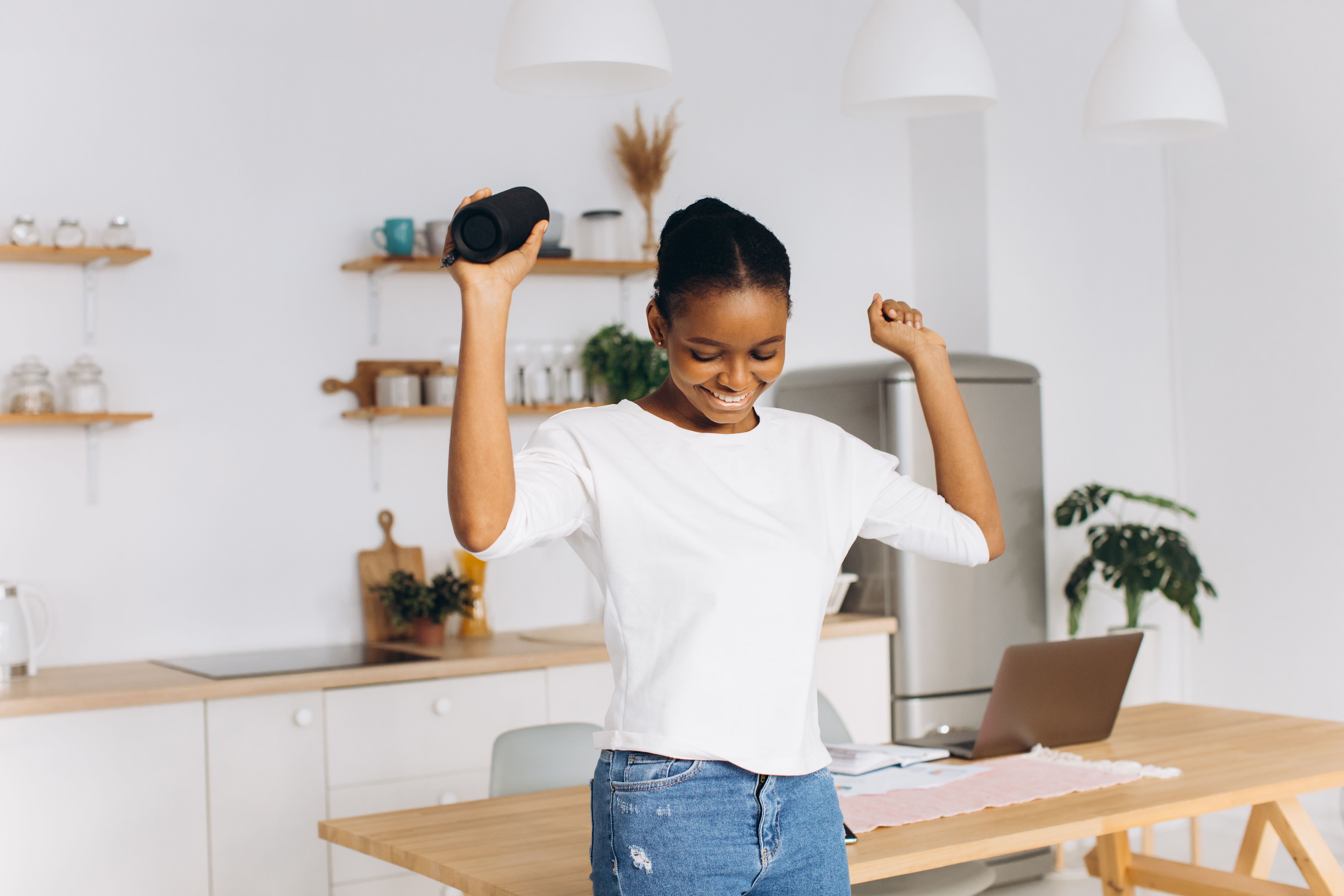 Woman holding a bluetooth speaker and dancing