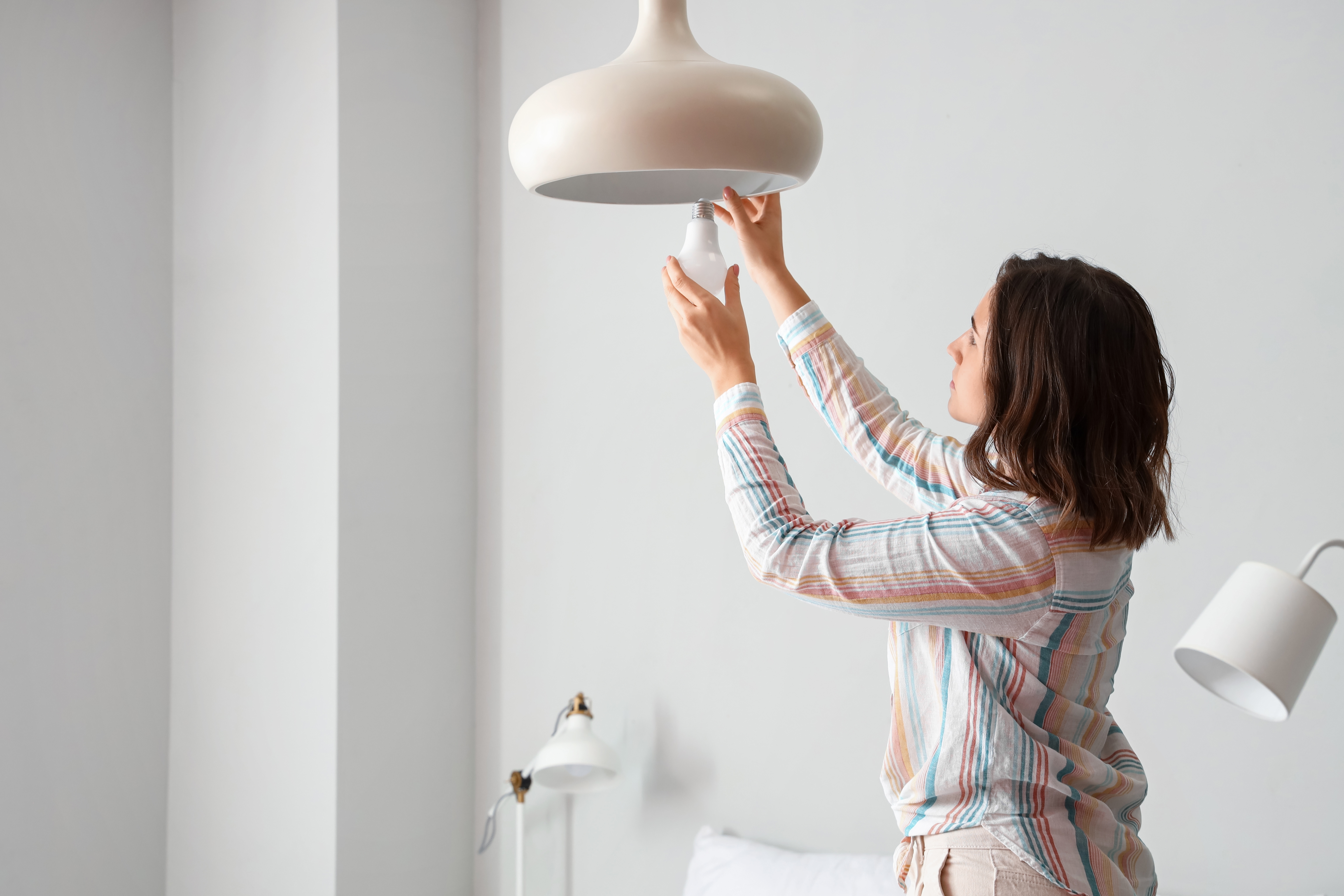 Woman installing an LED light bulb in an overhead light