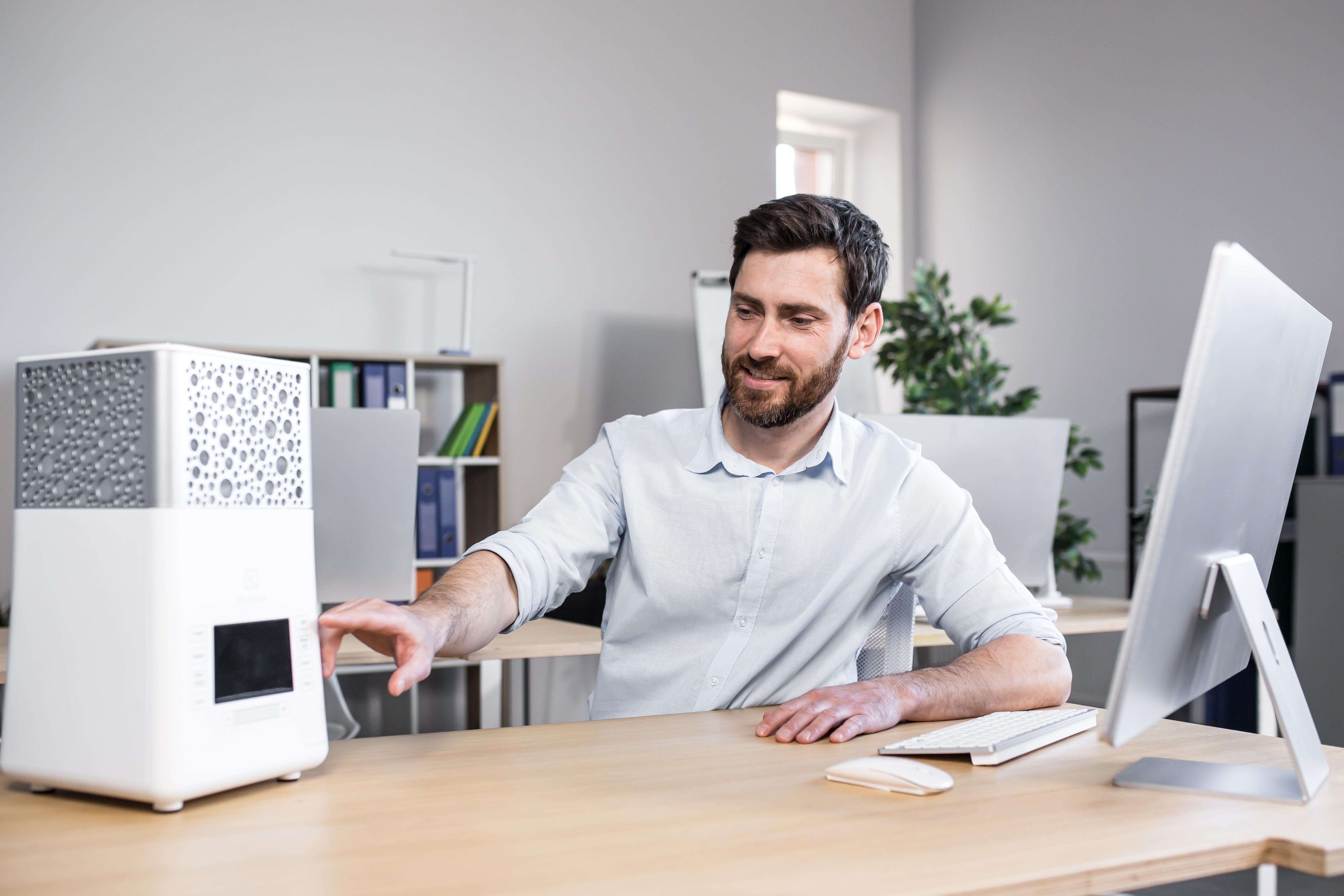 Man in an office turning on a portable air conditioner