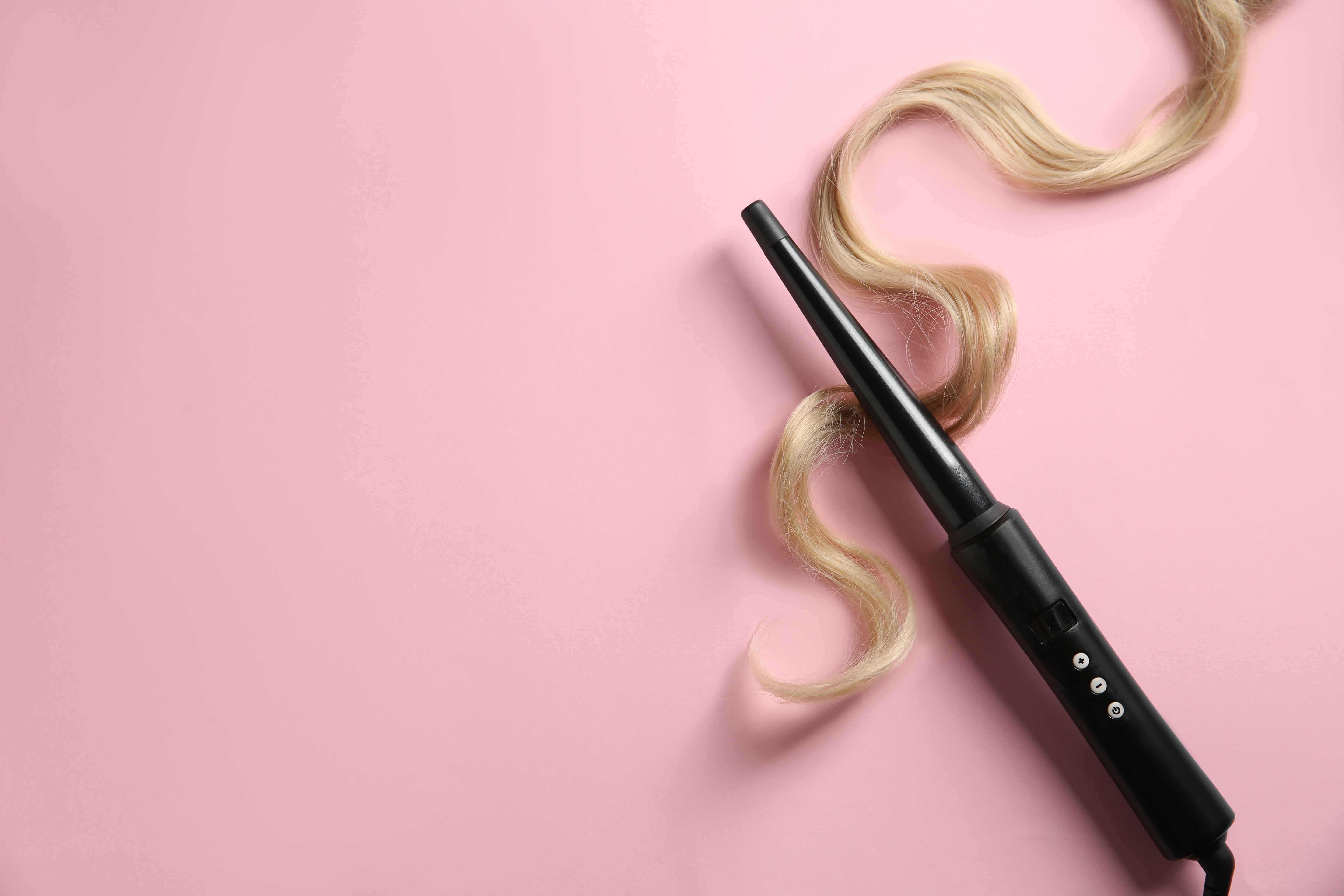 Curling wand and blonde hair set on a pink background