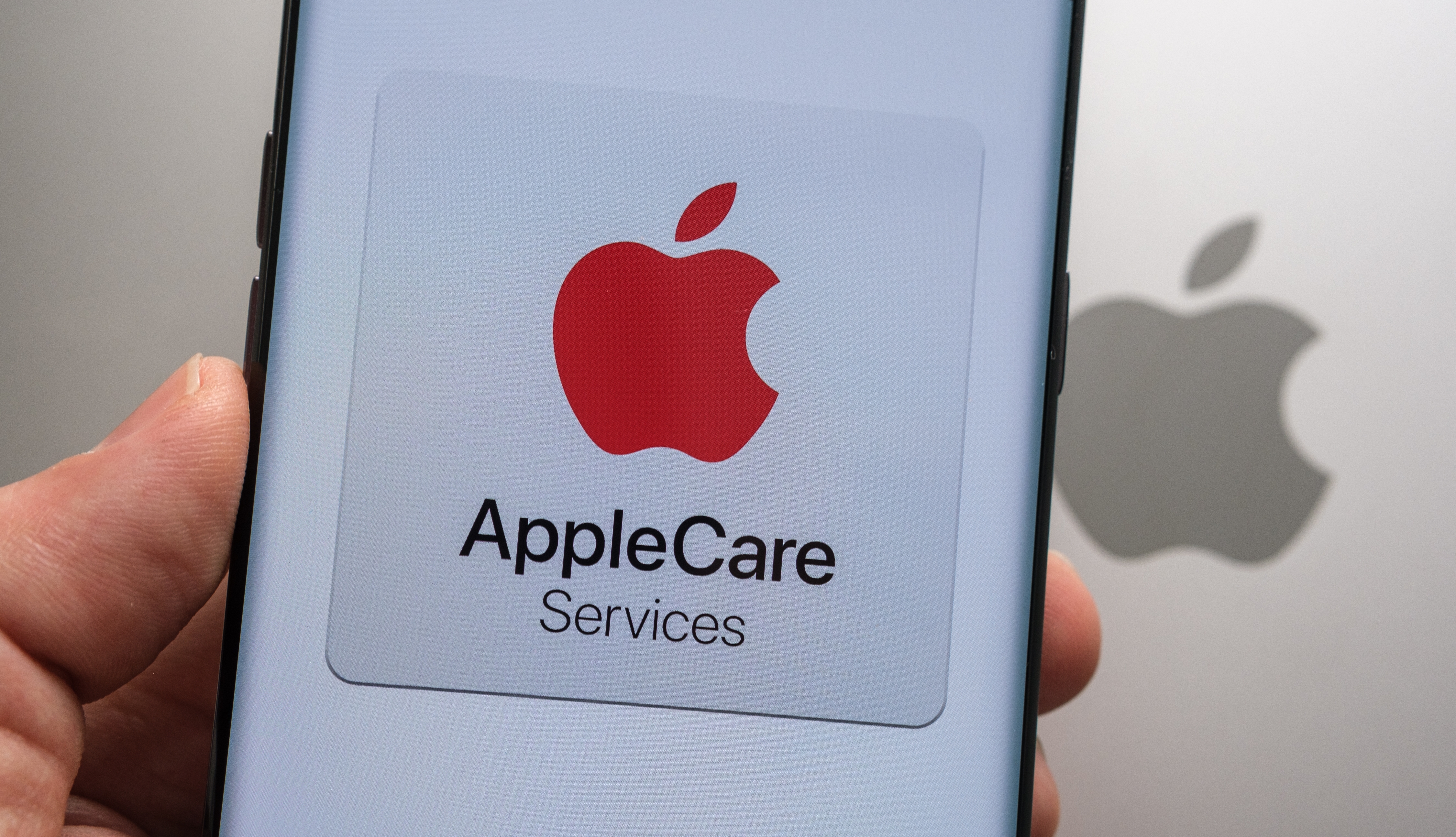 Person holding a smartphone with the AppleCare logo on it