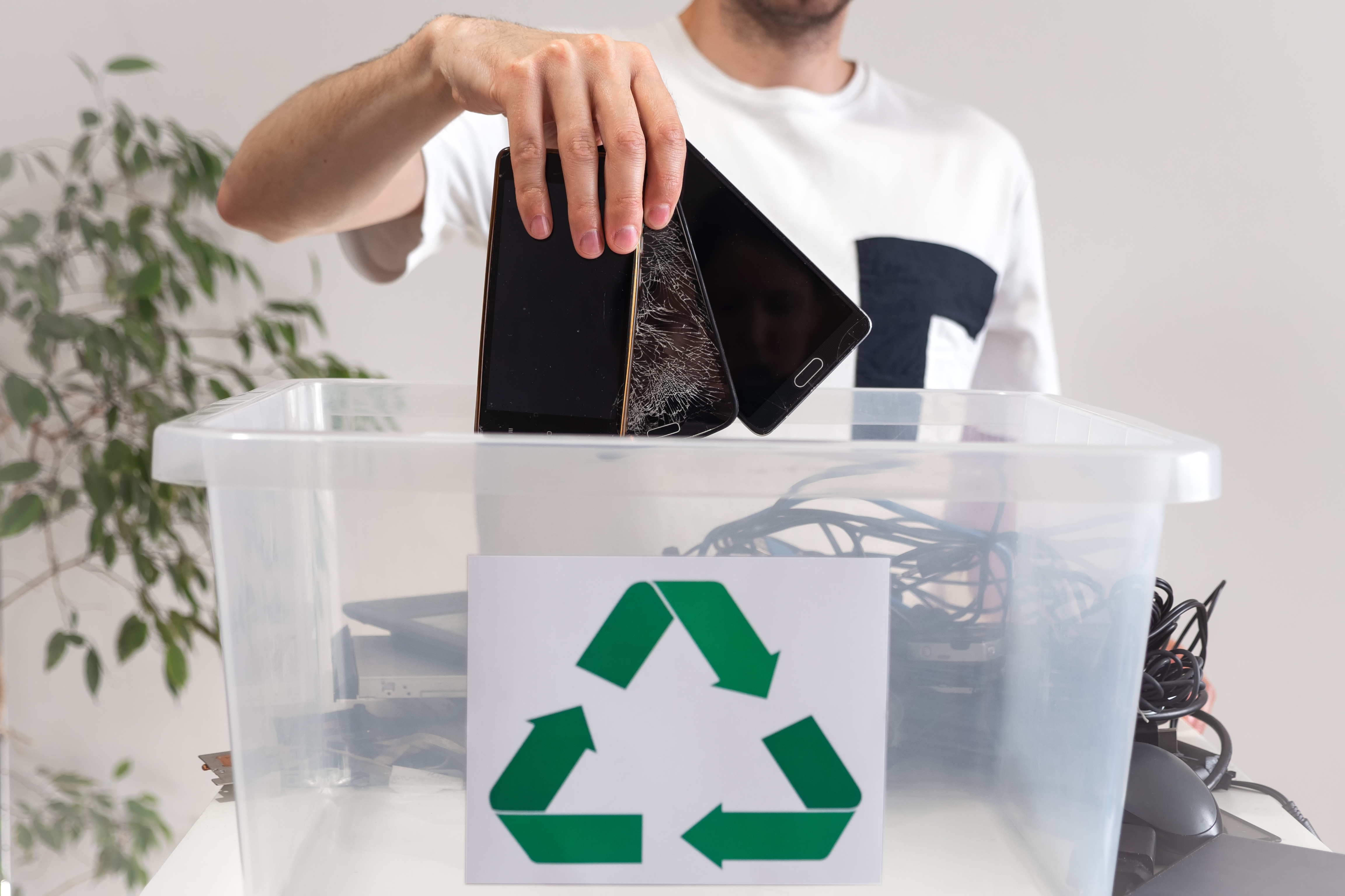 Man placing old smartphones into an electronics recycling bin