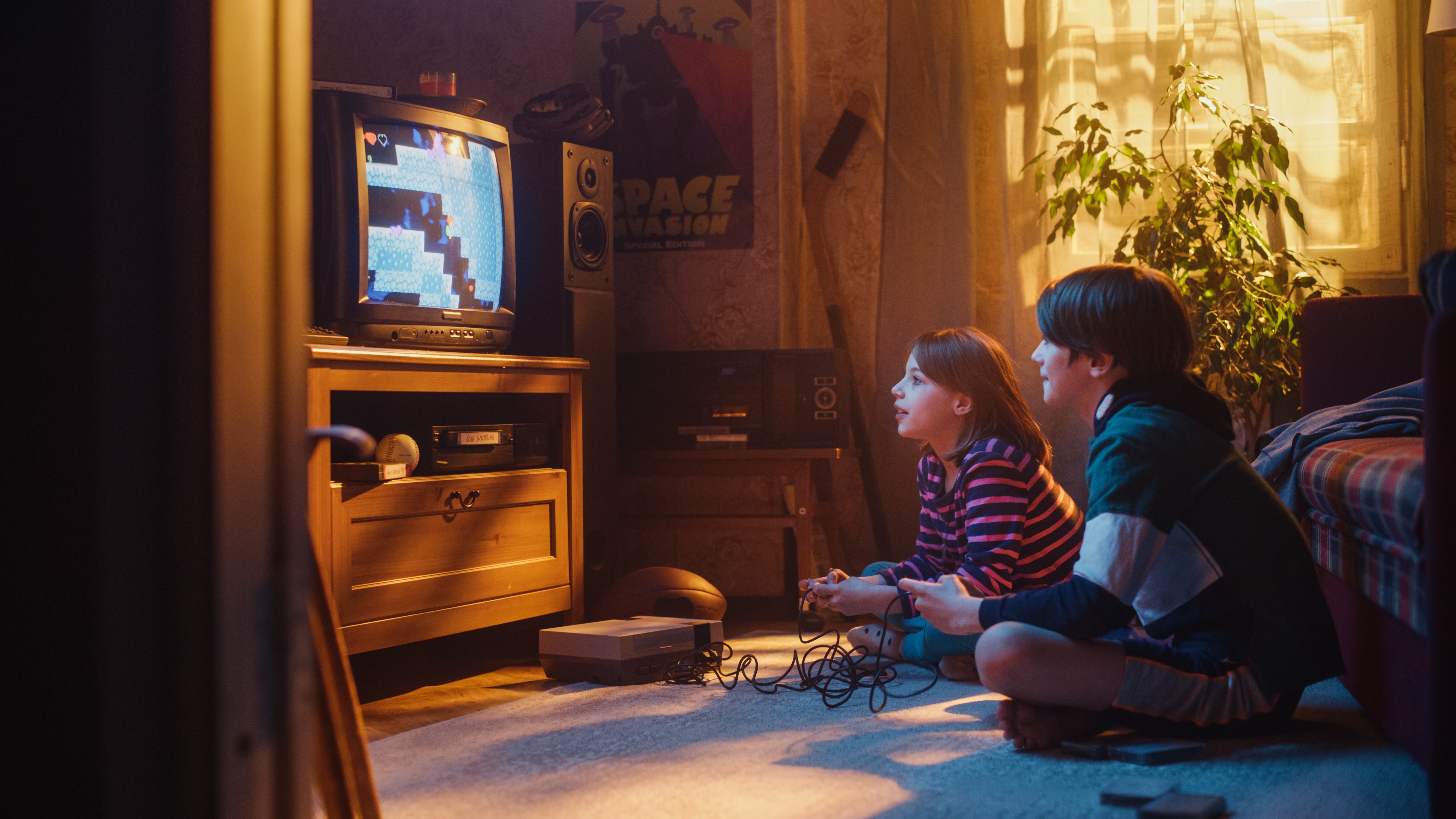 A boy and a girl sitting on the floor playing a retro video game