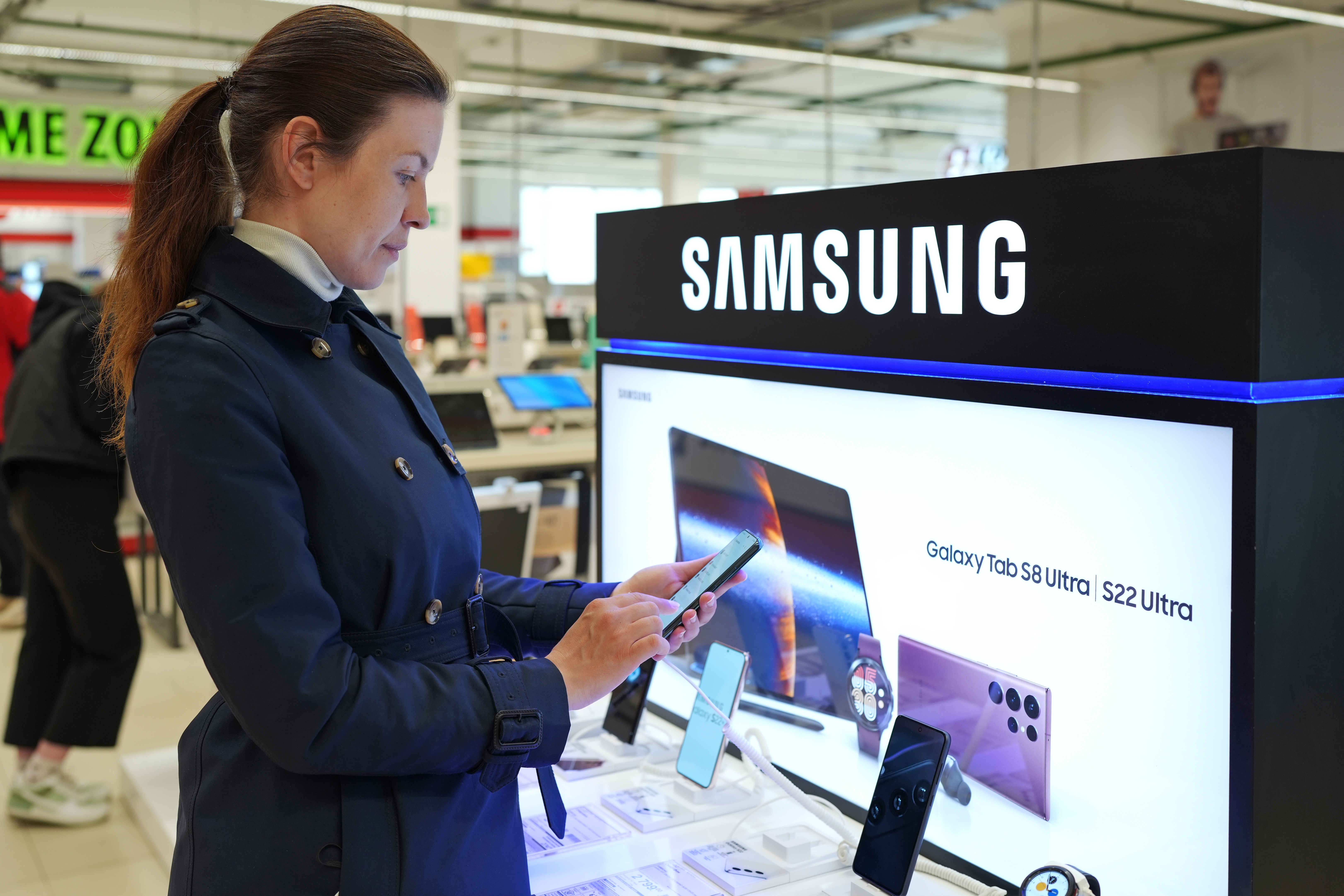 Woman standing at a Samsung kiosk on a phone