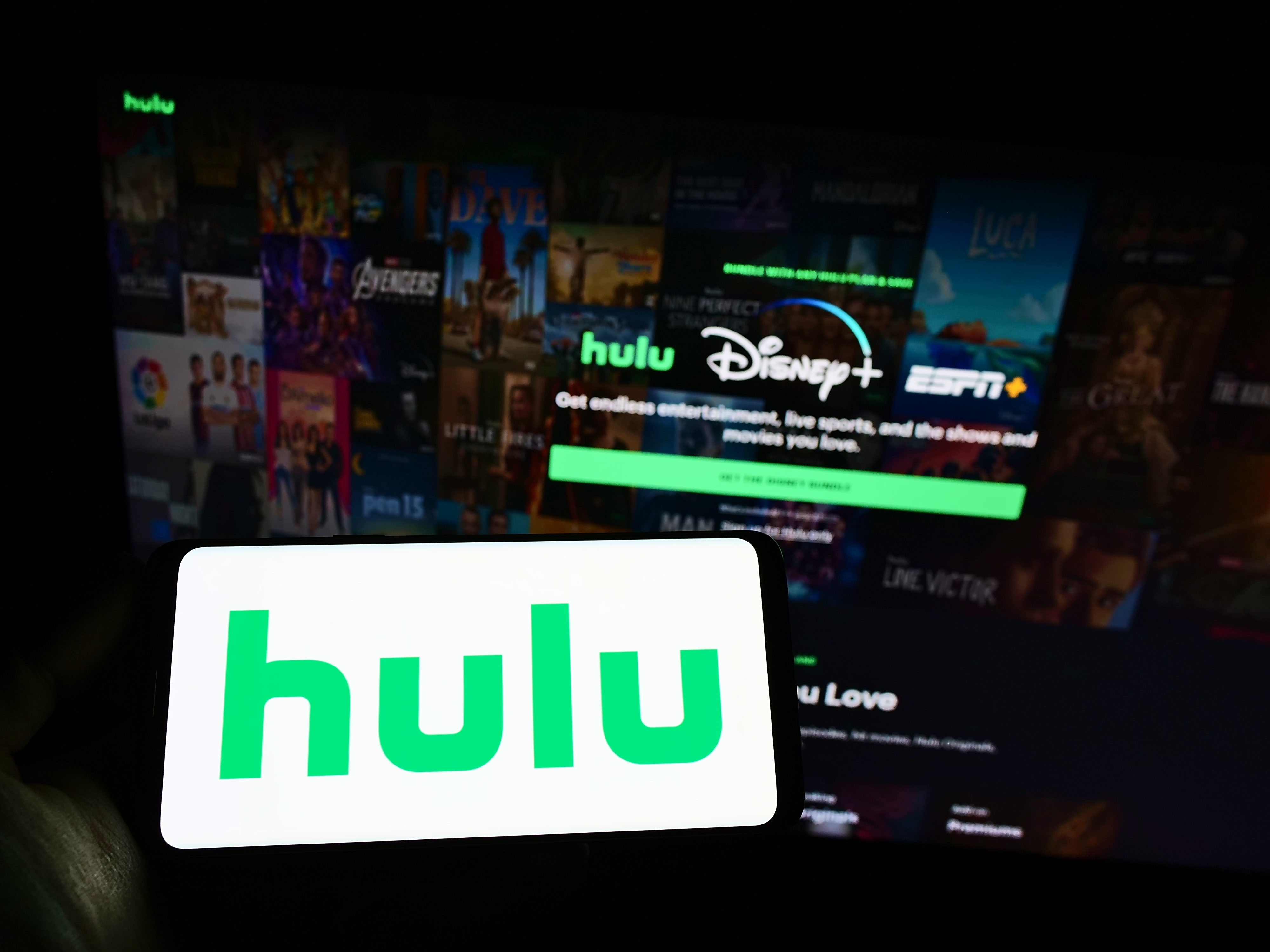 Smartphone showing the Hulu logo with a laptop behind it showing the Hulu bundle