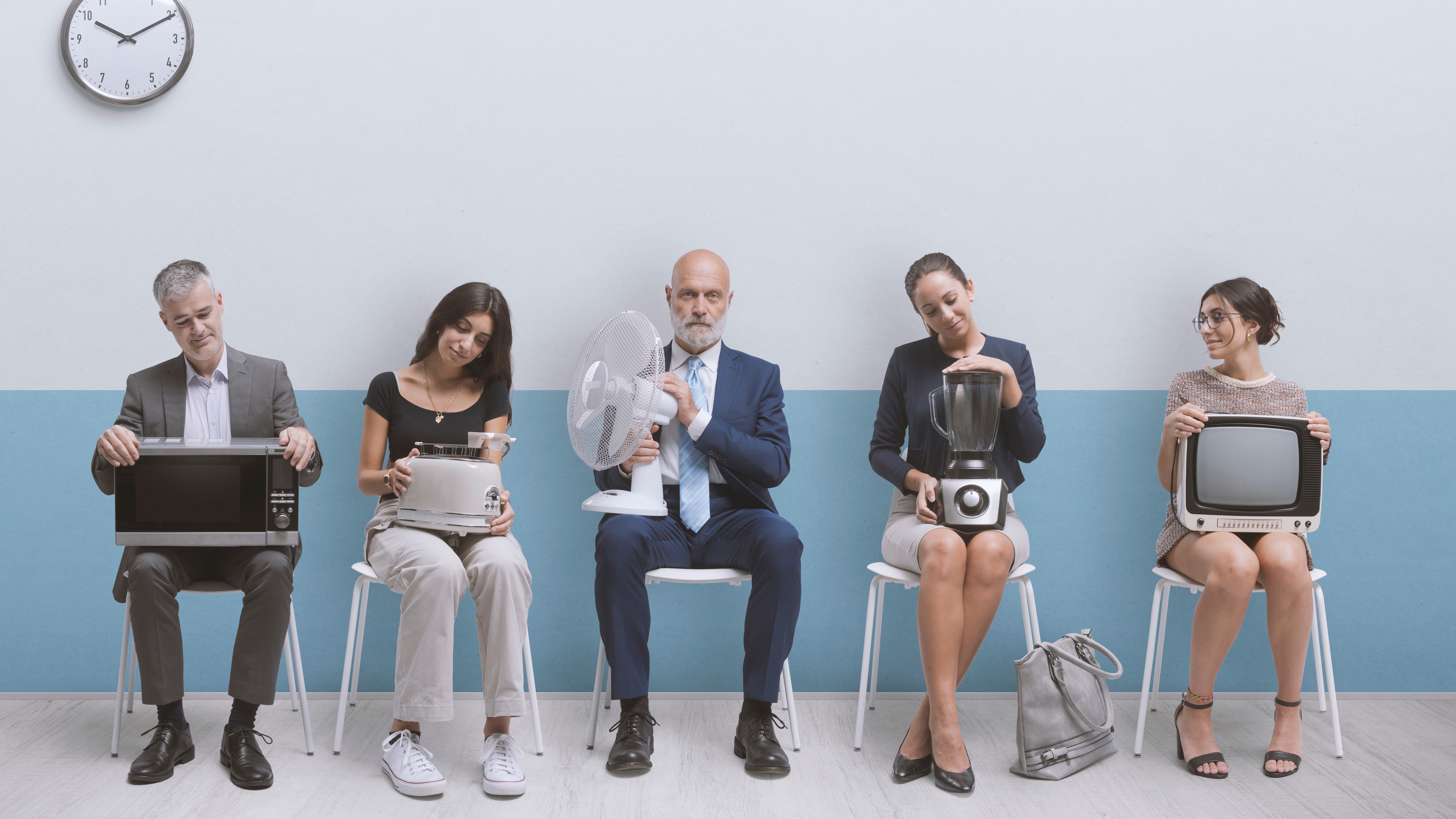 People sitting on chairs holding small appliances