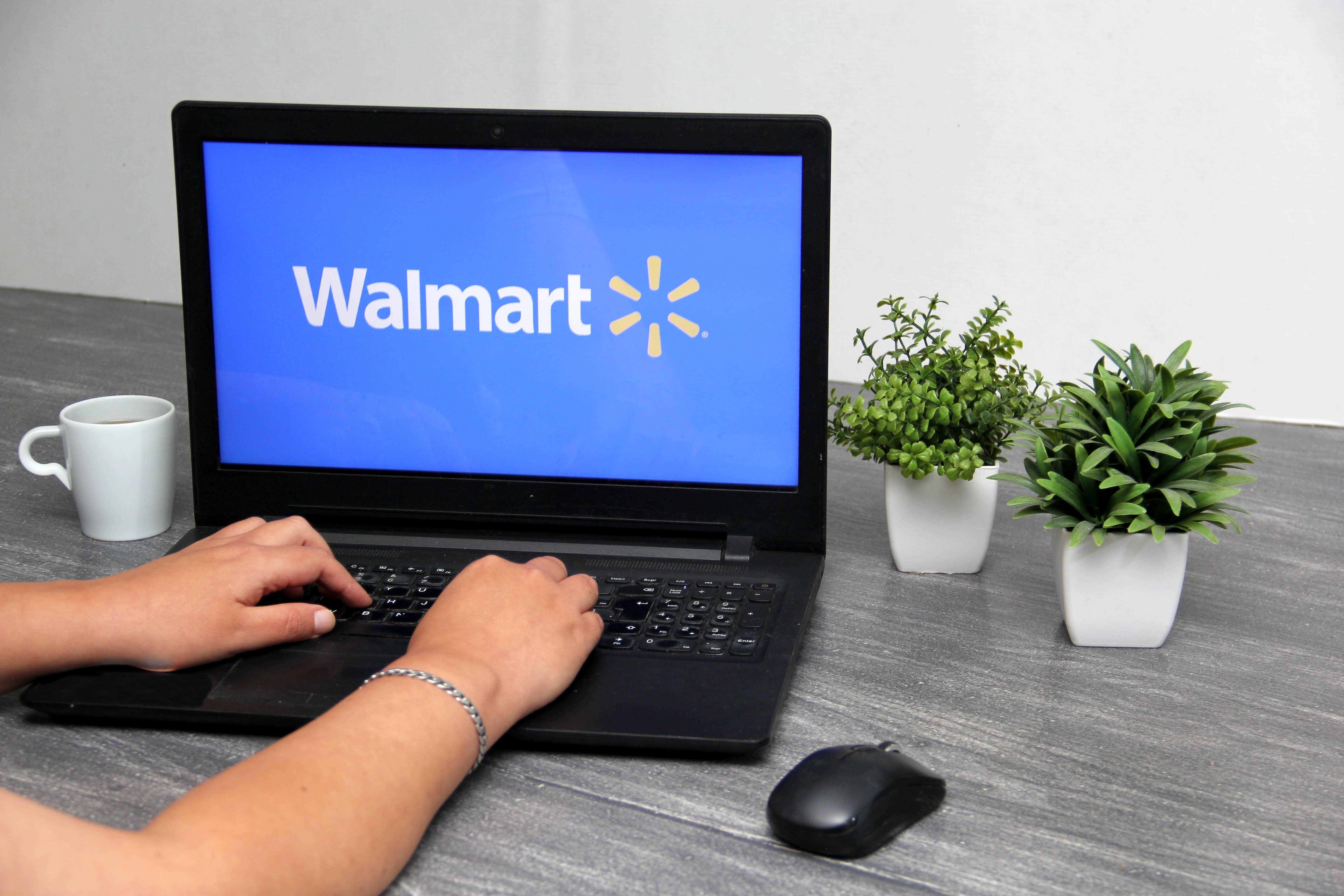 Person typing on a laptop with the Walmart logo on it