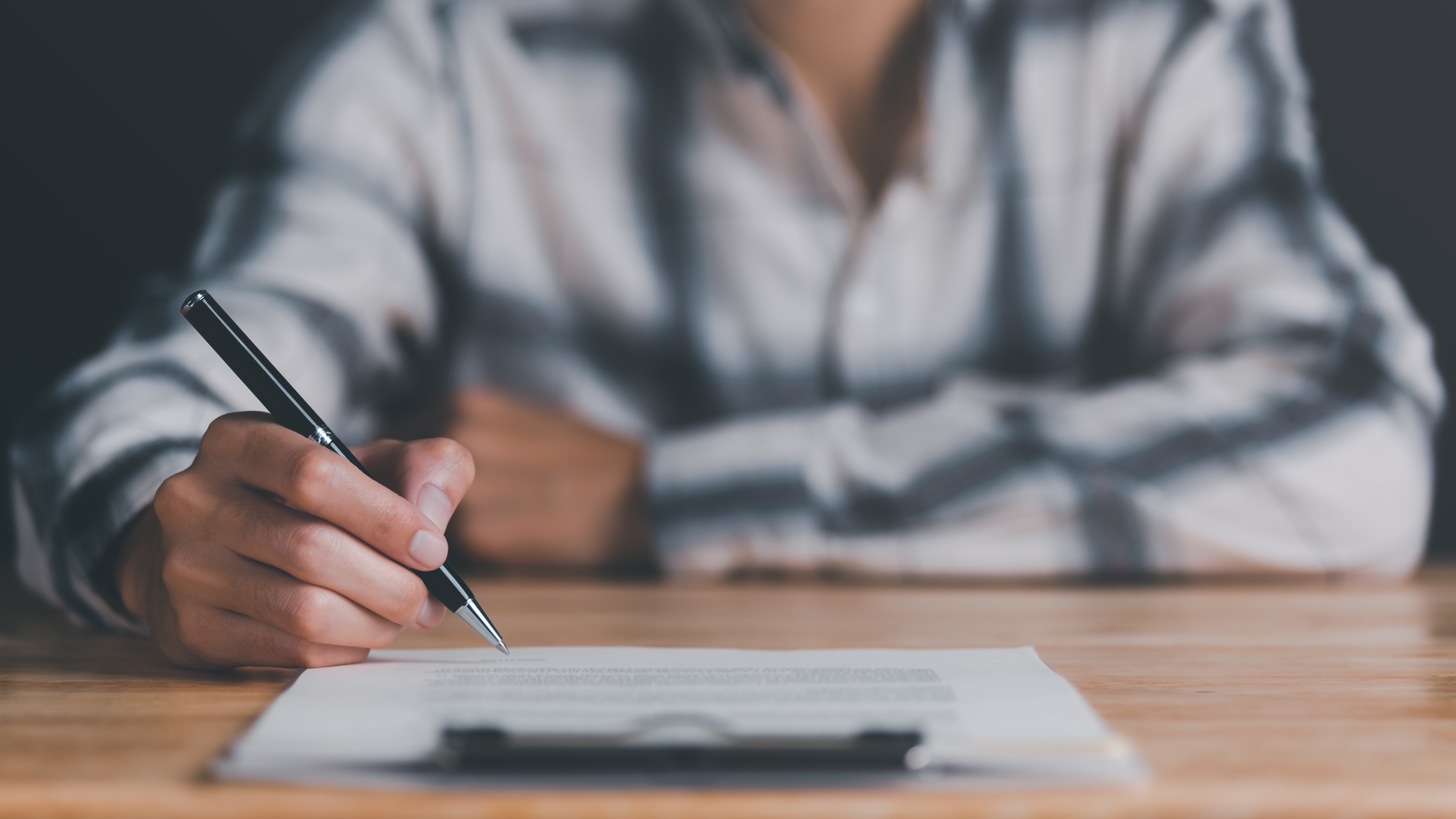 Person signing paperwork attached to a clipboard