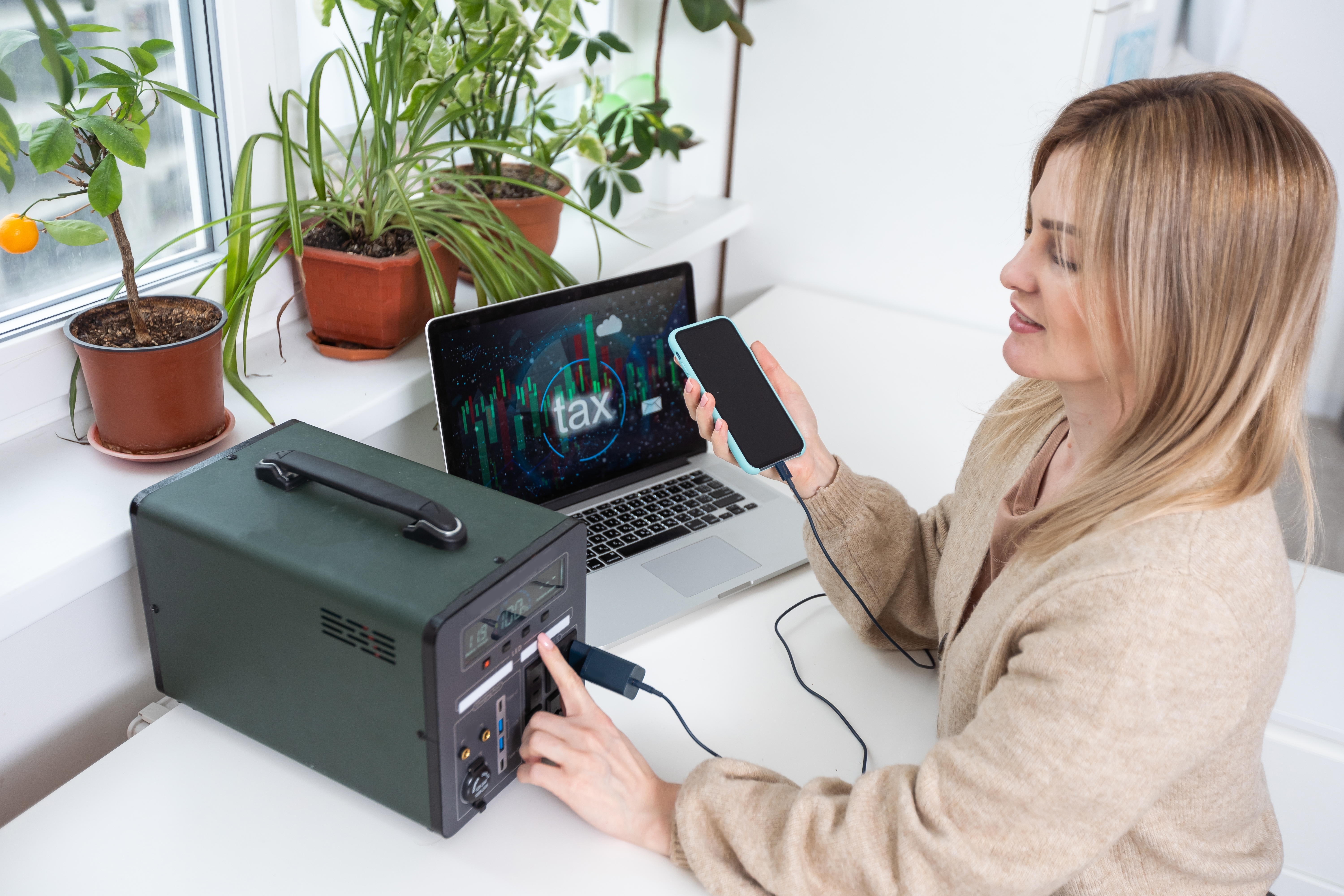 Woman charging her phone and computer with a portable power station