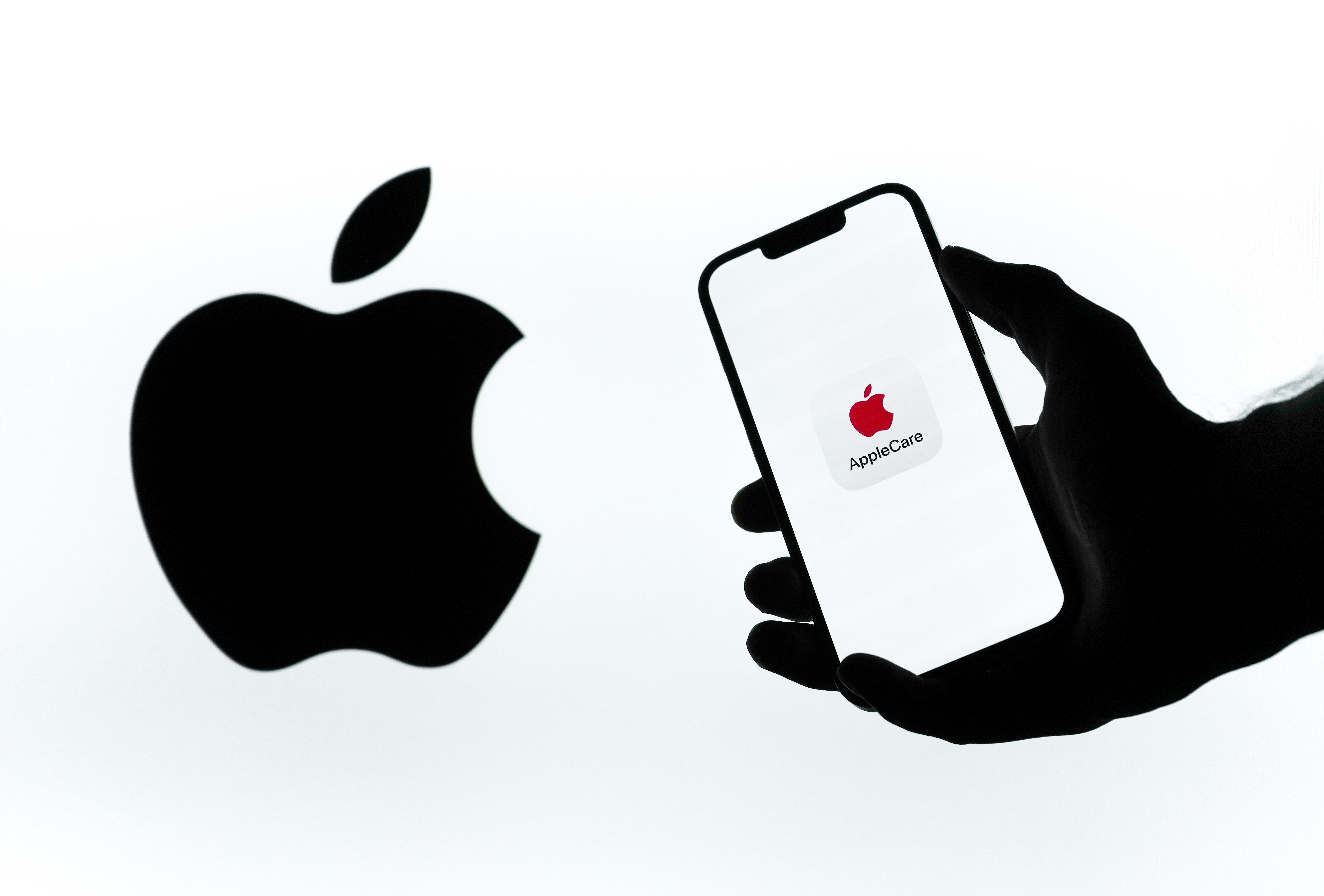 Person holding an iPhone with the AppleCare logo on it in front of the Apple logo