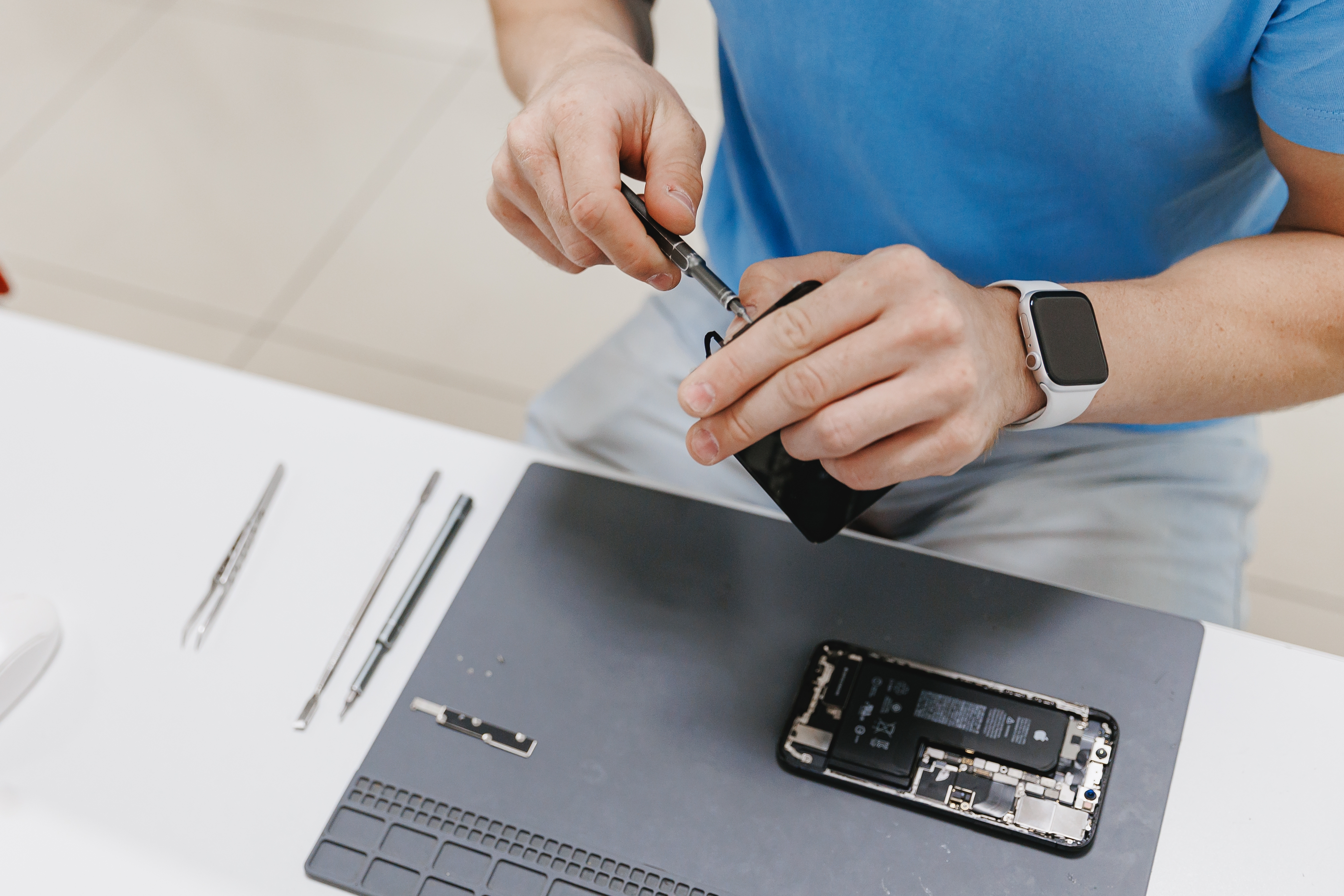 Person sitting at a desk repairing a smartphone