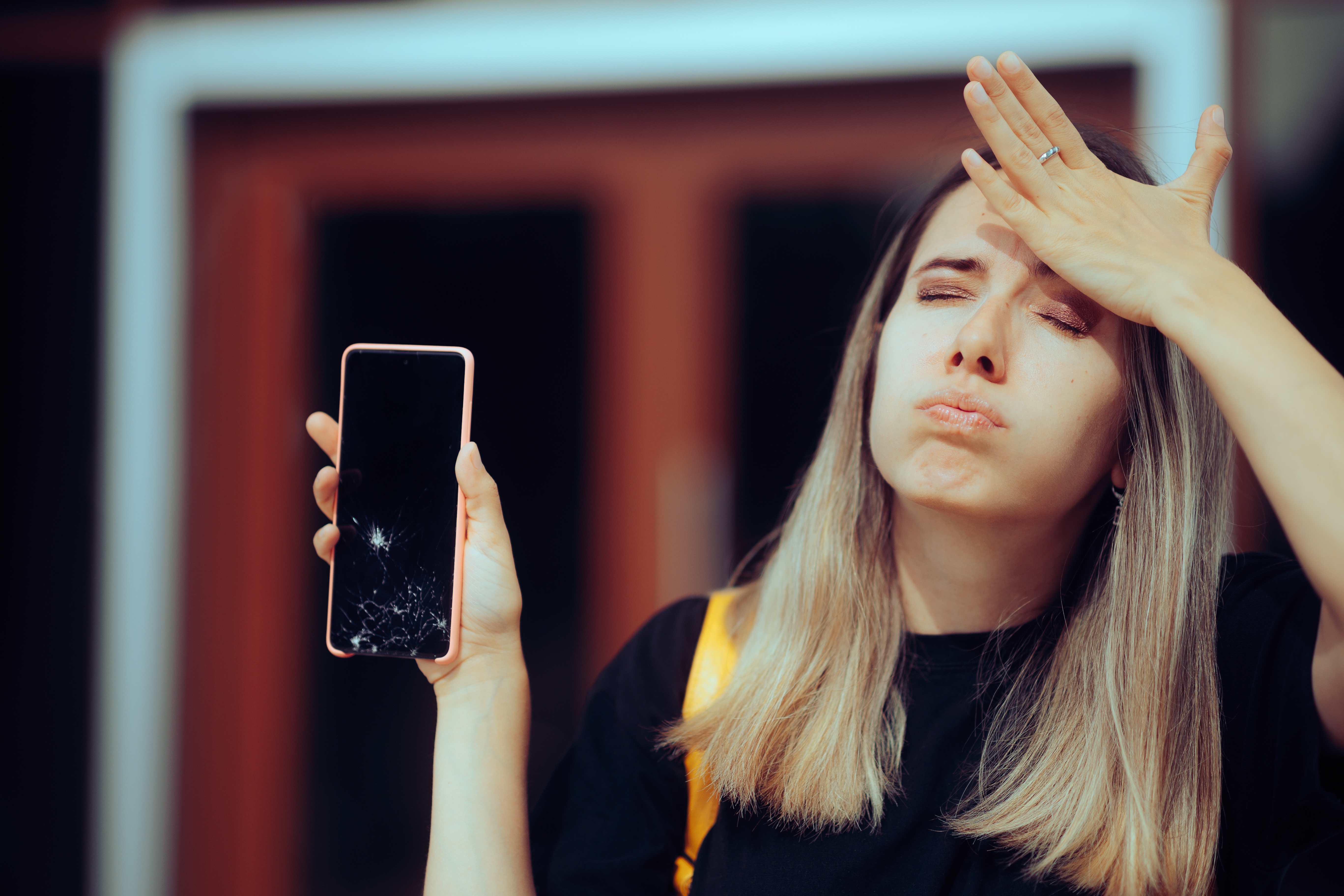Woman holding her smartphone that has a cracked screen