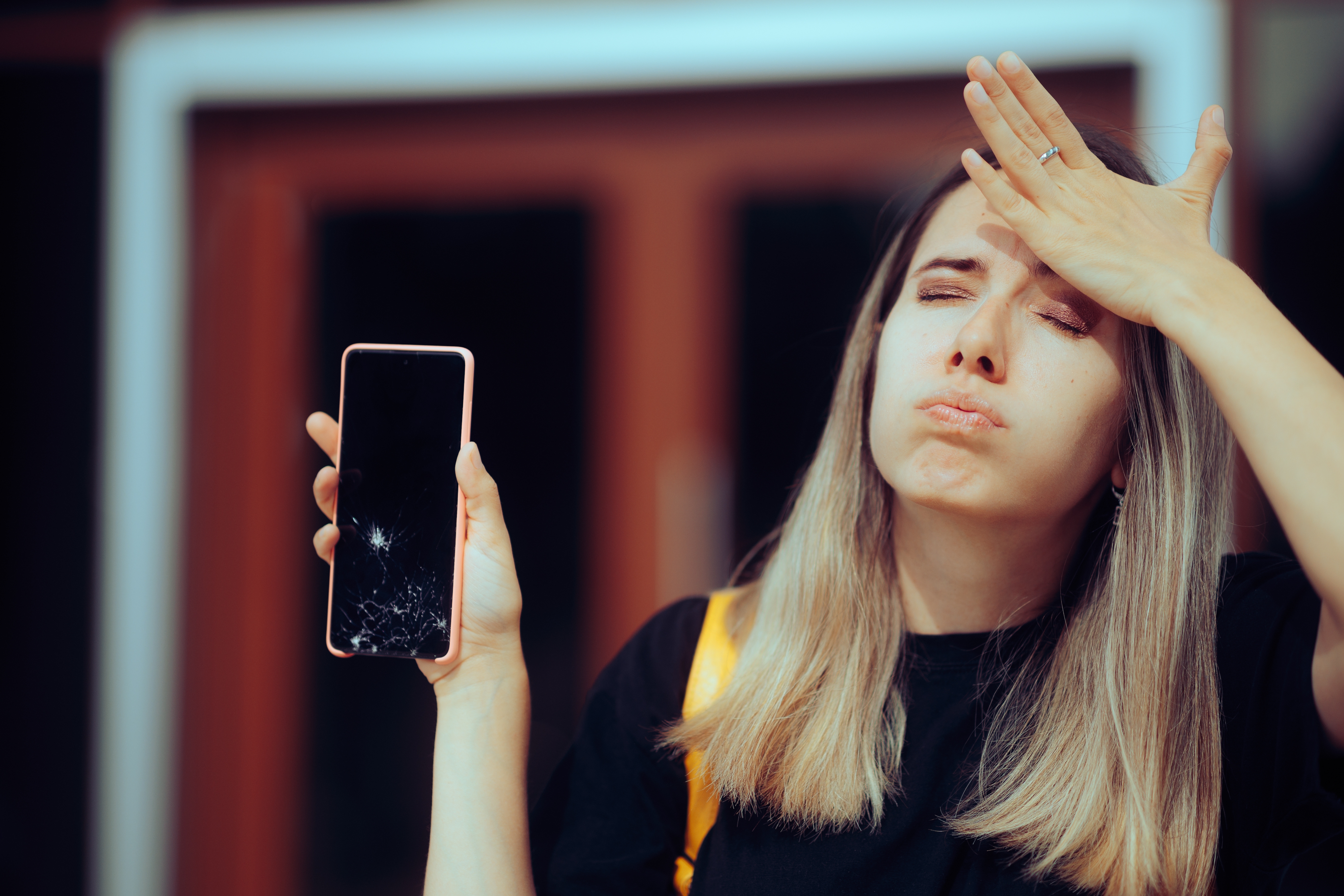 Woman holding her smartphone that has a cracked screen