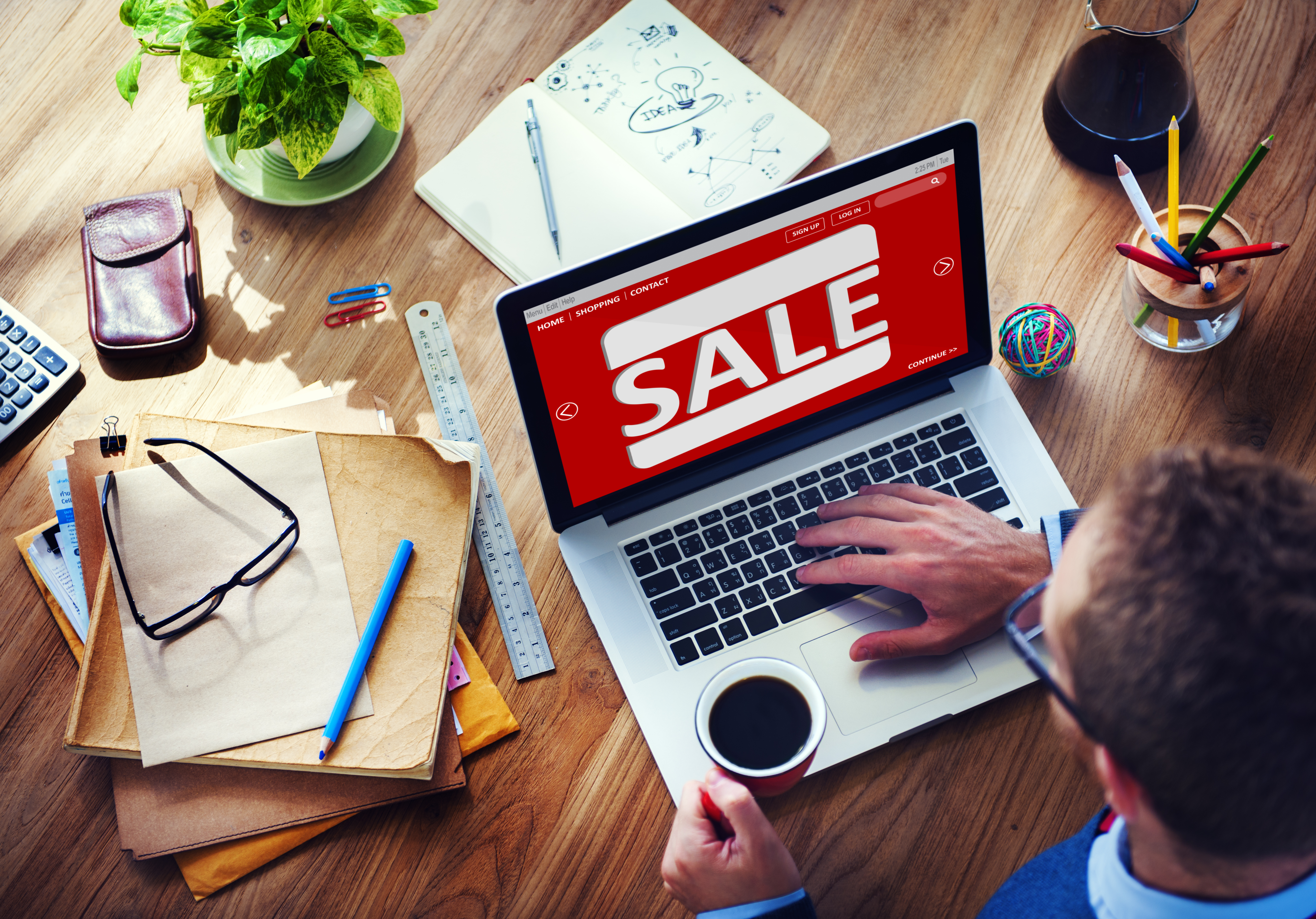 Man drinking coffee browsing a sale on the computer