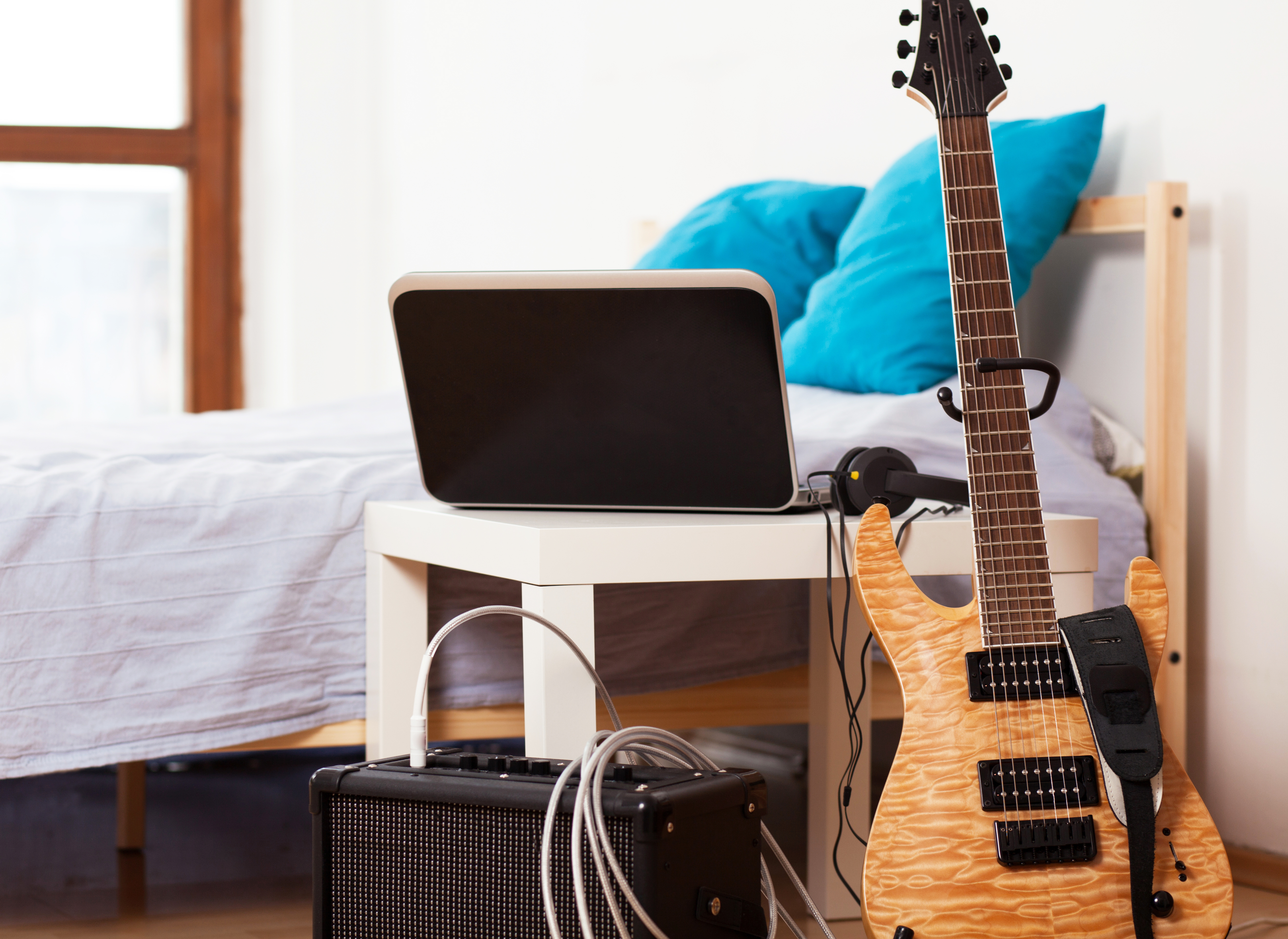 Guitar with an amp and other accessories next to it leaning against a table