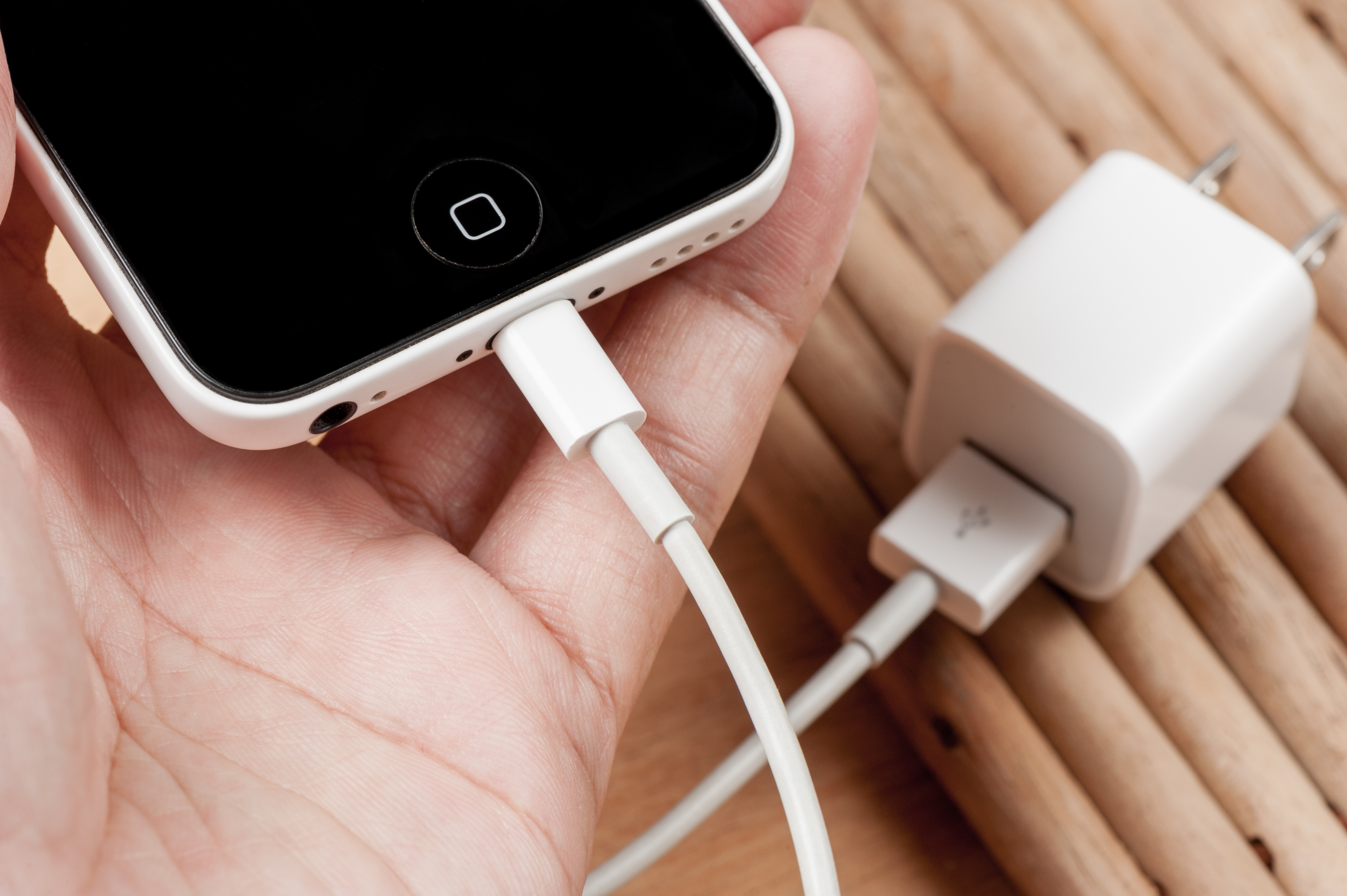 Person holding an iPhone with a lightning cable charger plugged into it