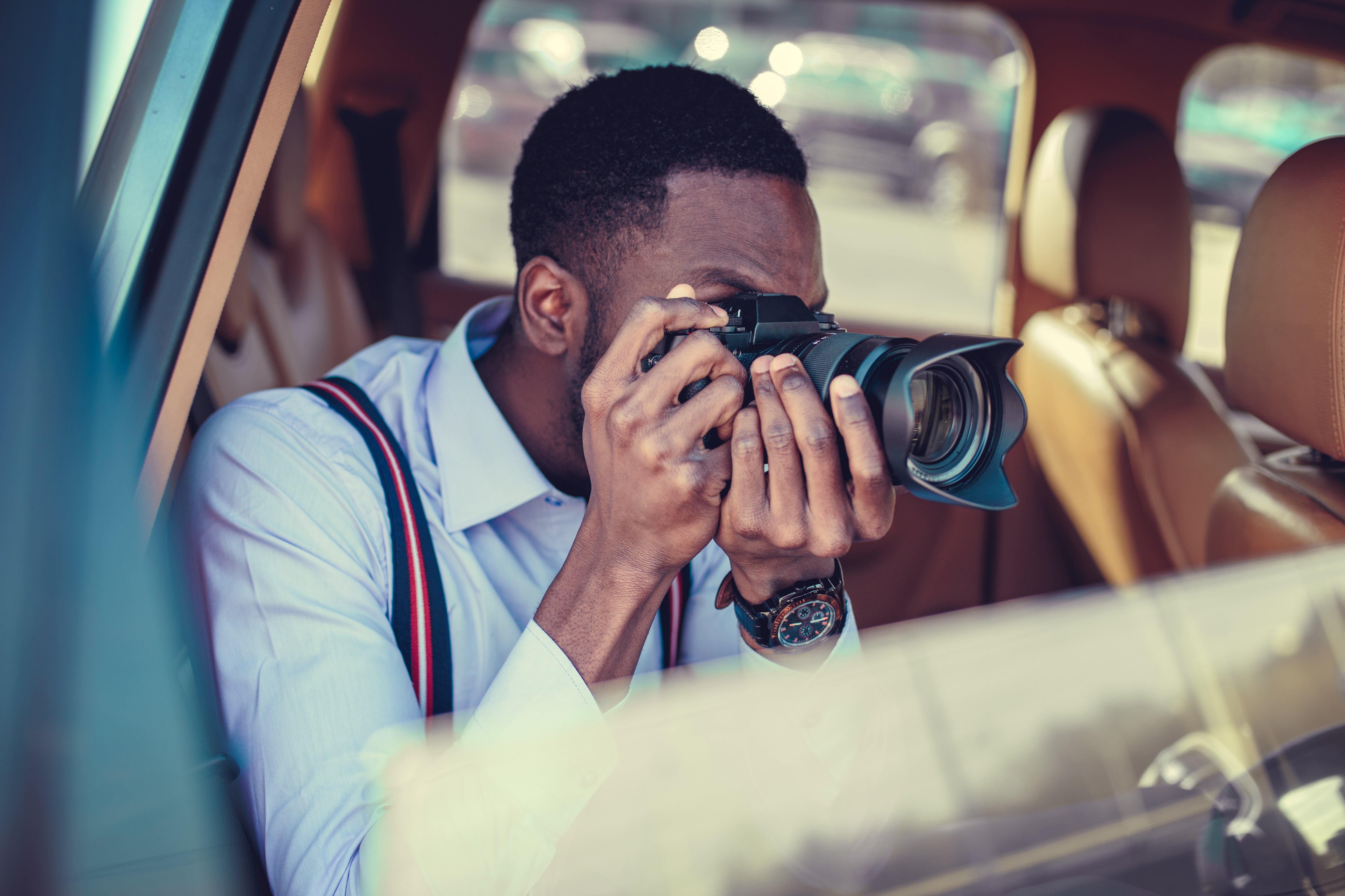 Man sitting in a car taking a picture through an open window