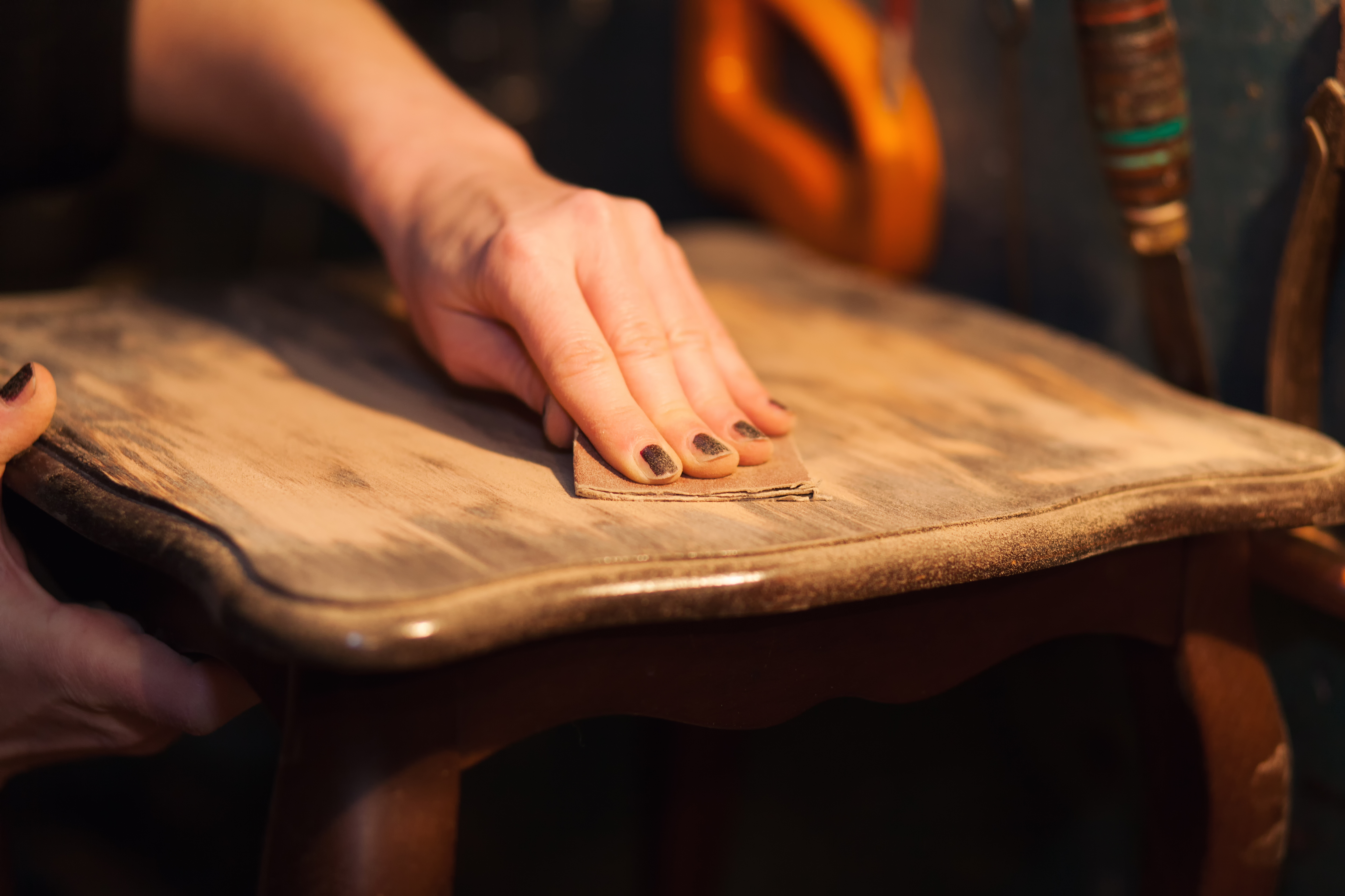 Woman sanding a piece of wood furniture