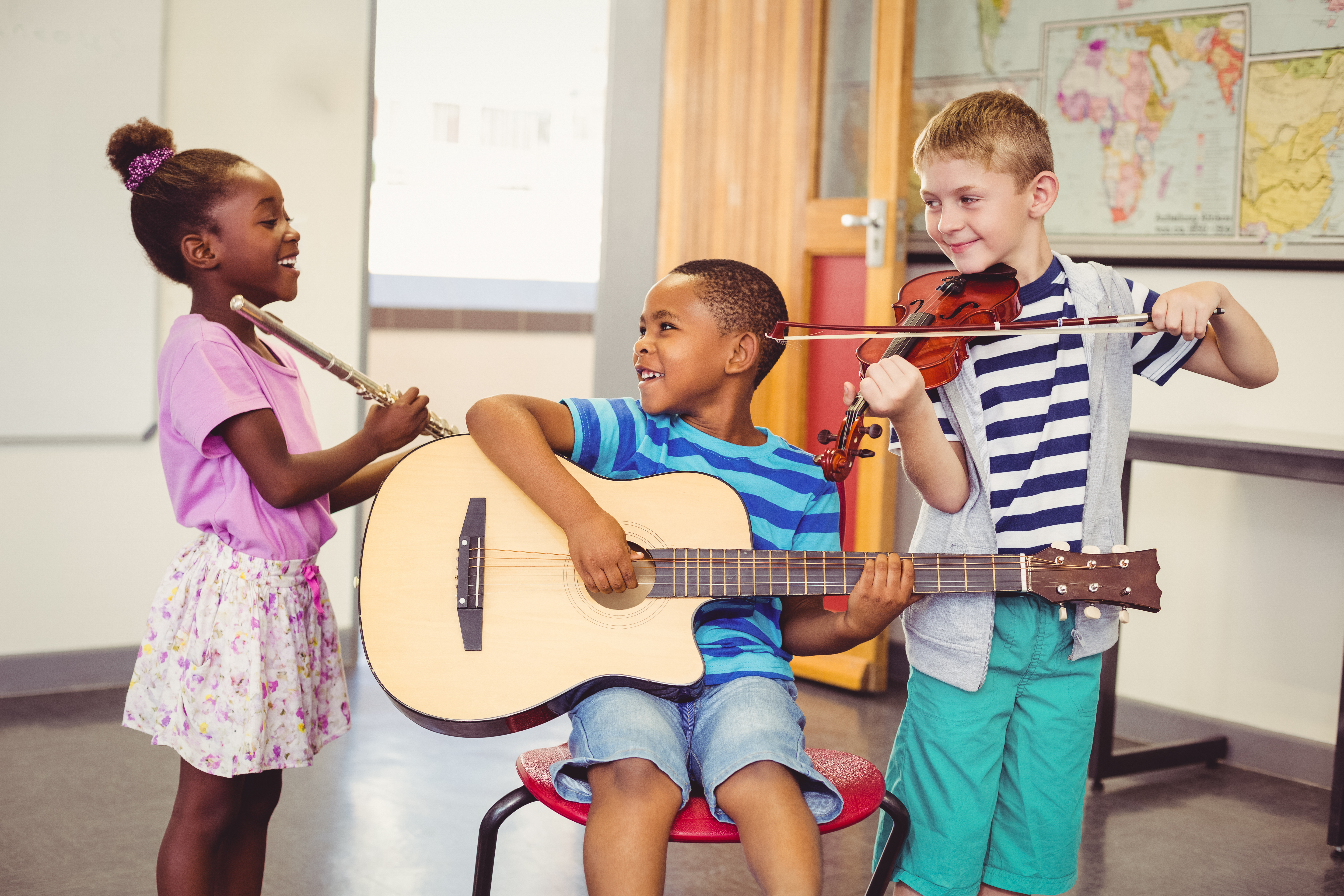 Three kids each holding different musical instruments