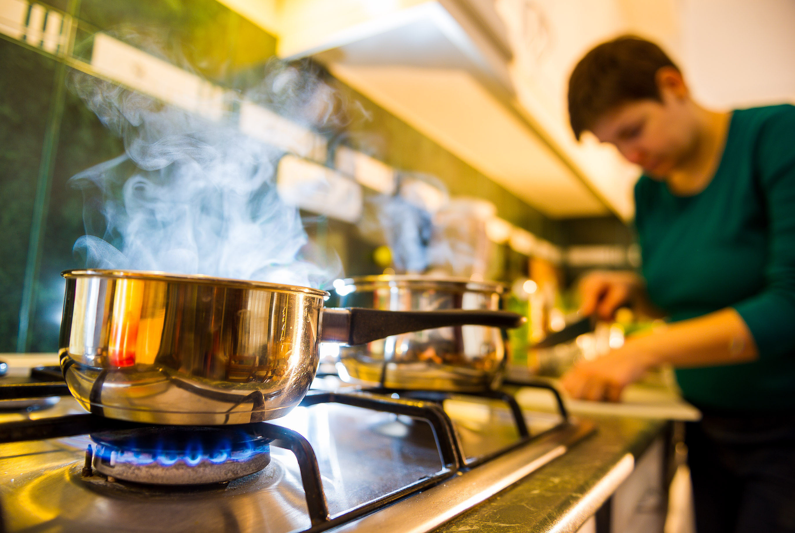 Woman cooking with a pot on a gas stove