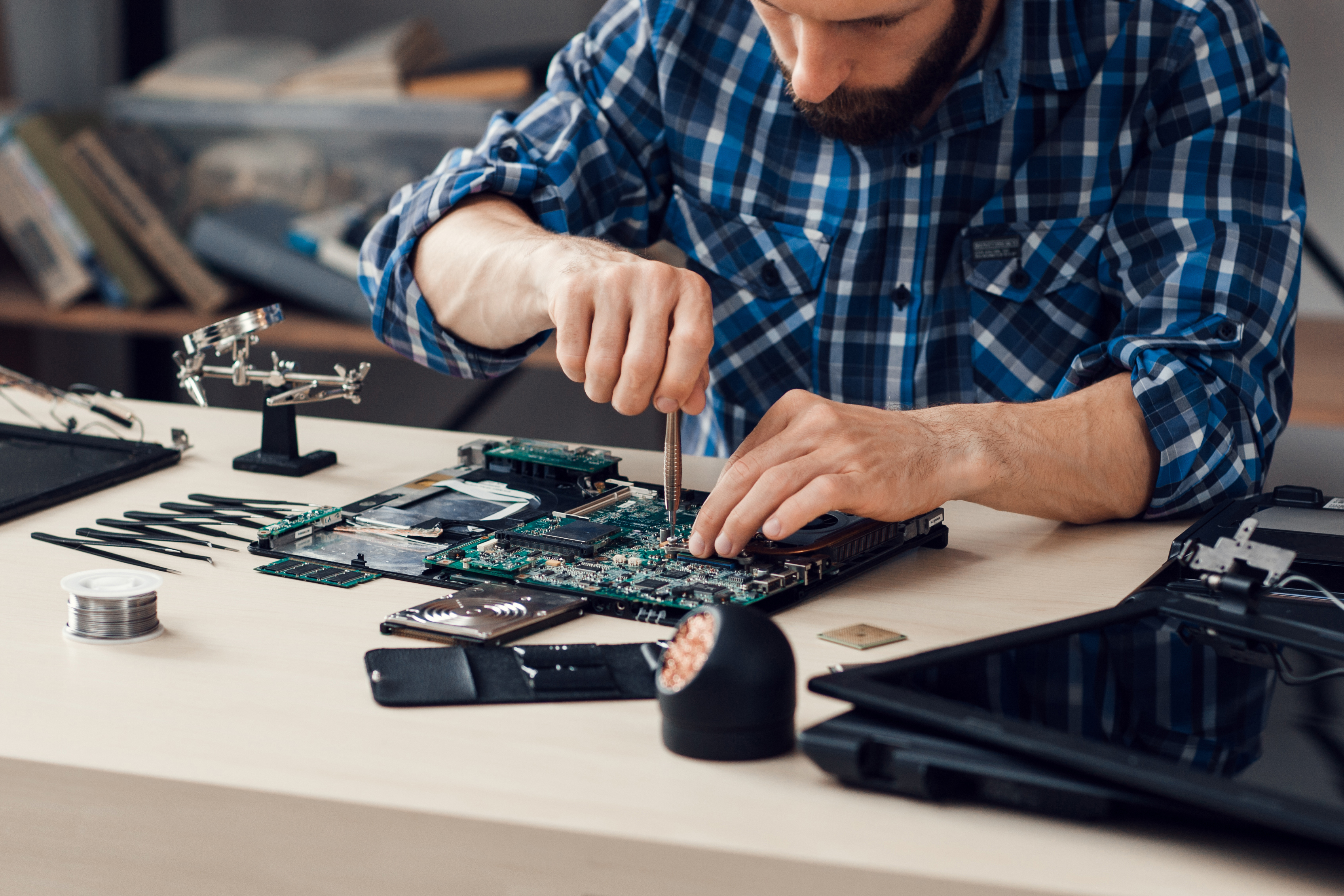 Man sitting at a table repairing a laptop
