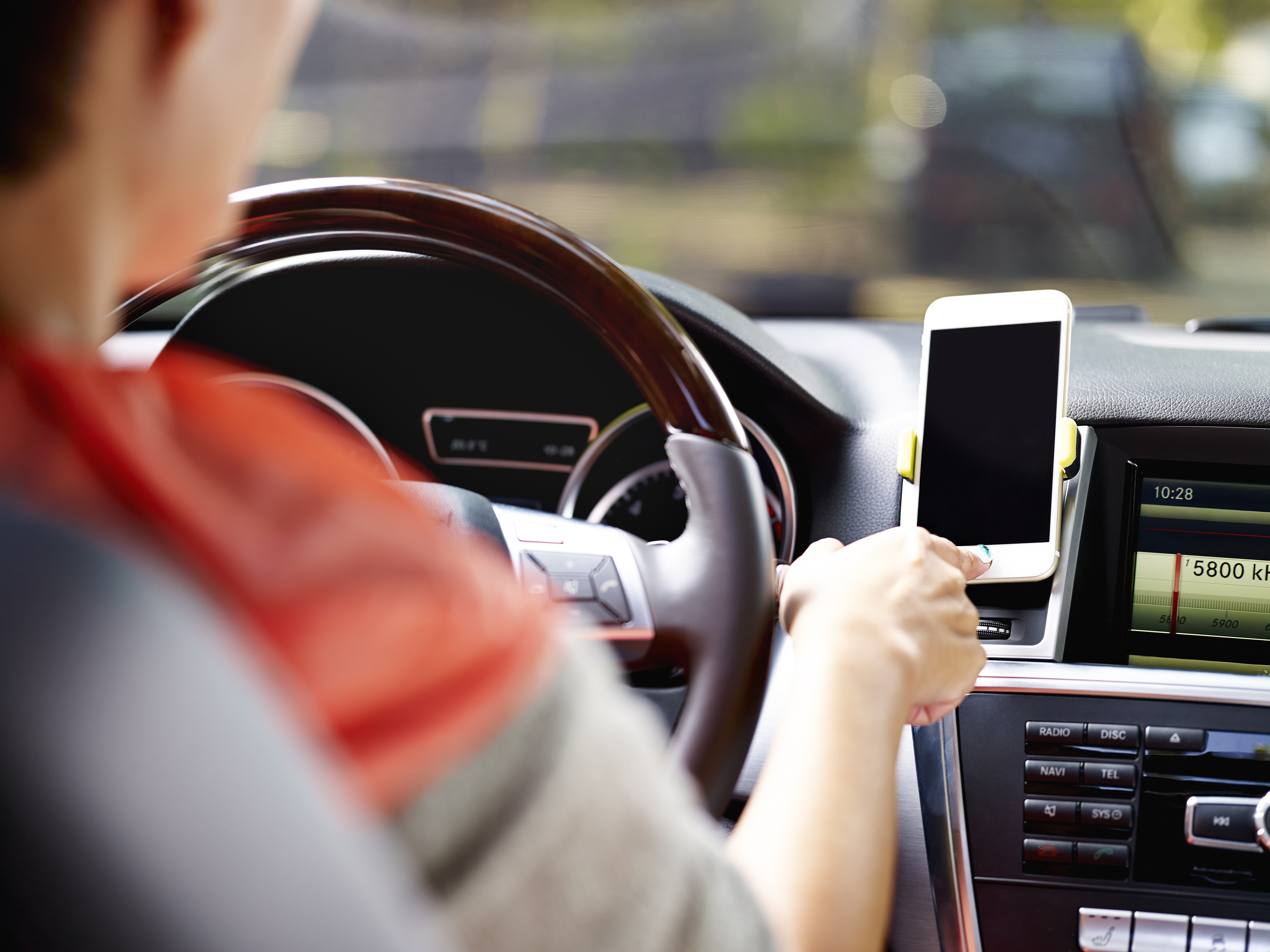 Man using his white smartphone on a car mount while driving