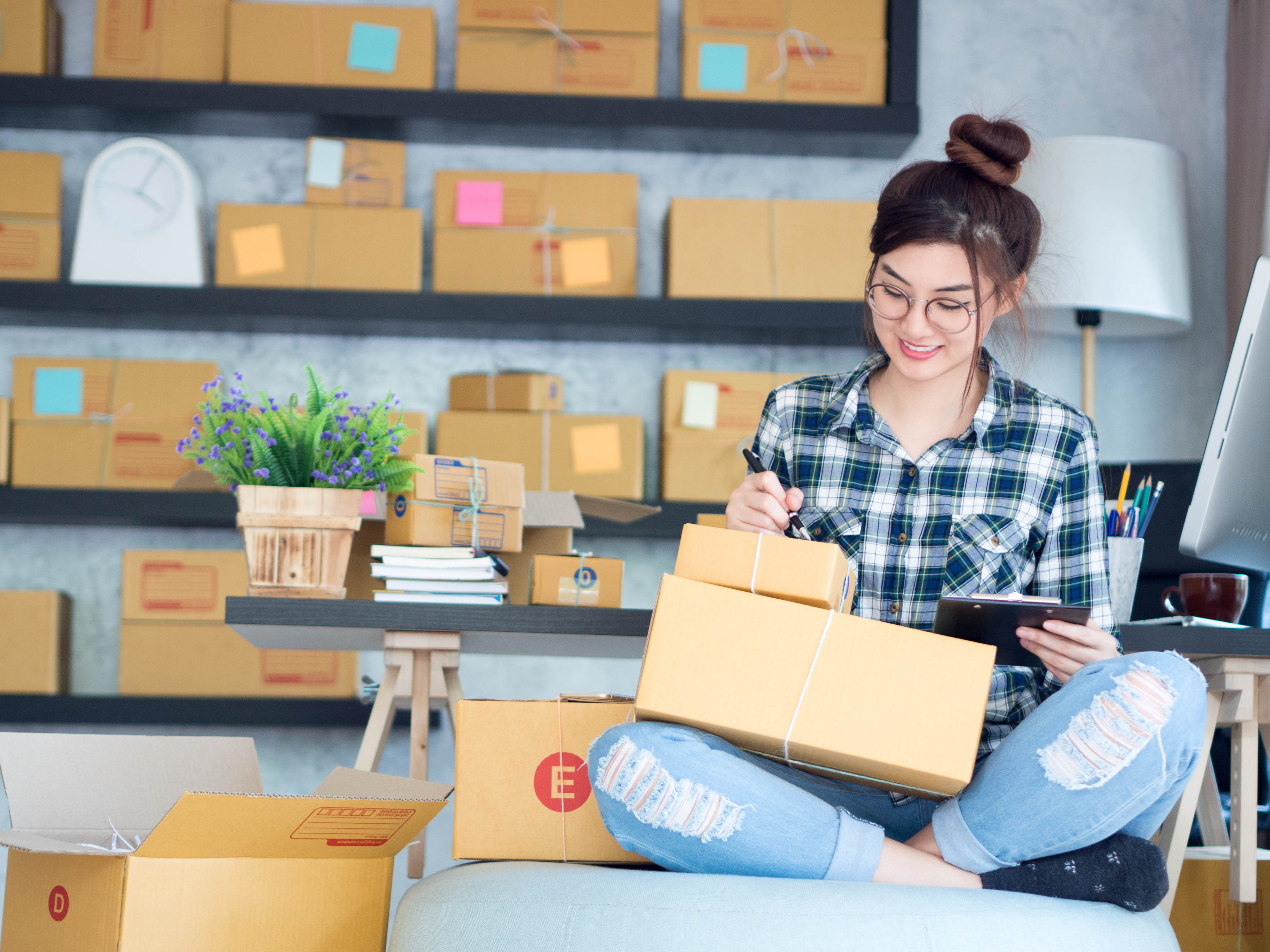 Woman sitting on a chair holding a stack of boxes and making notes