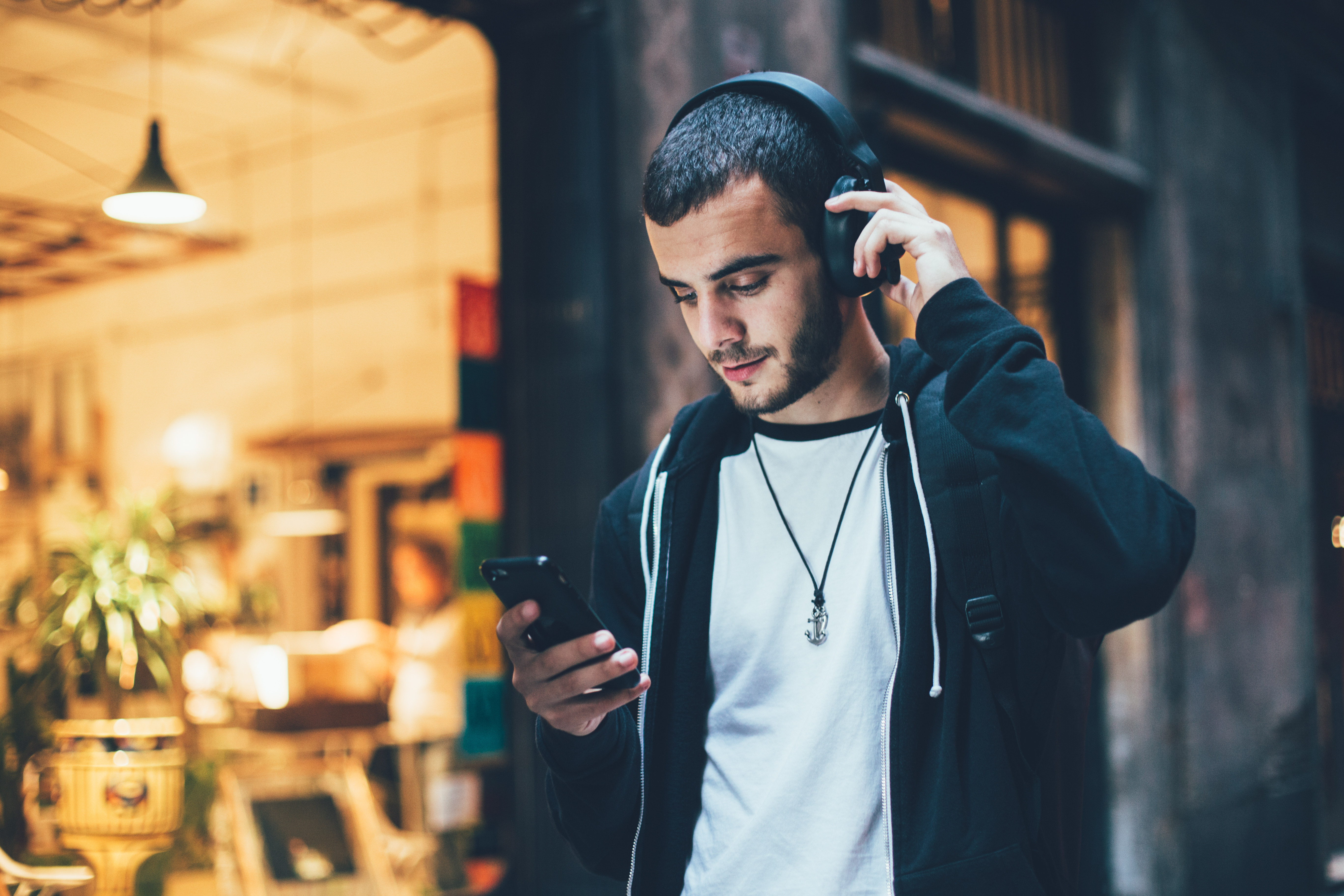 Man looking at his phone adjusting his over-ear headphones